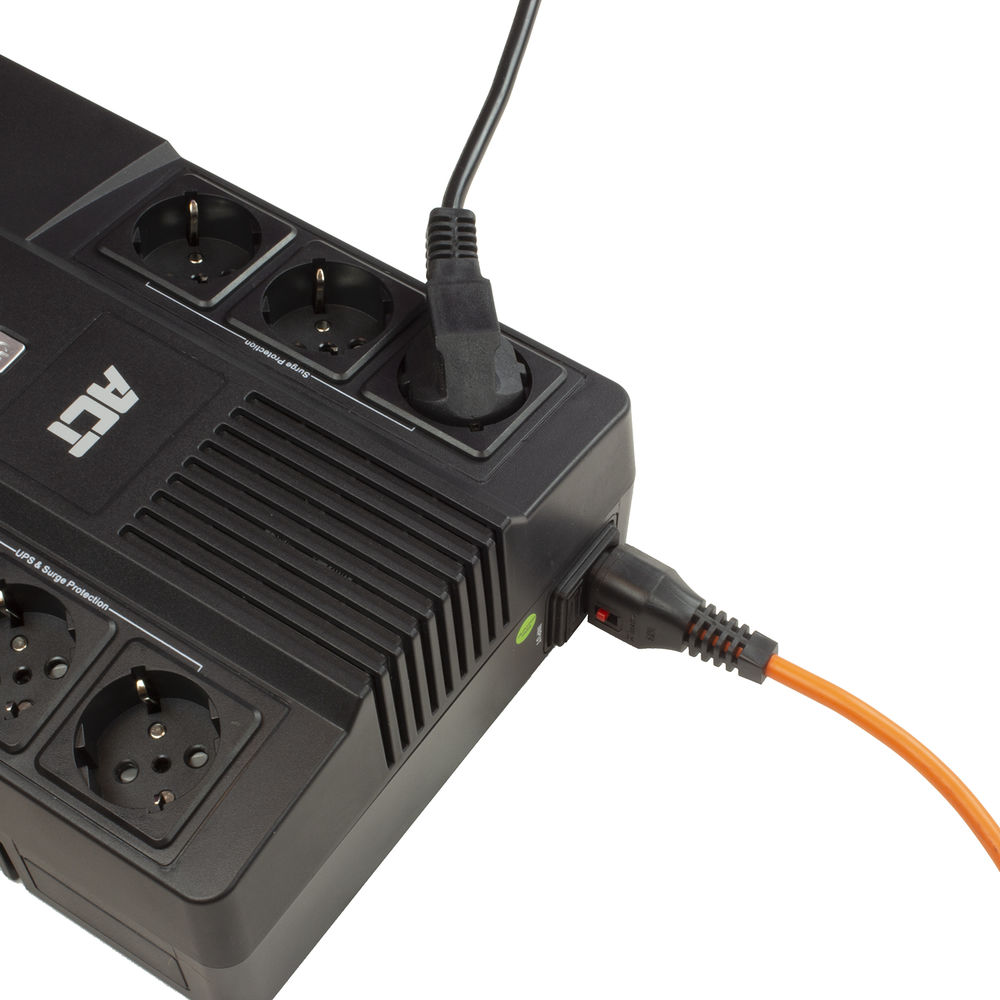 Eine schwarze Steckdosenleiste mit mehreren Steckdosen, in die Stecker gesteckt sind. Ein oranges Kabel ist angeschlossen. "ACT"-Etikett sichtbar.