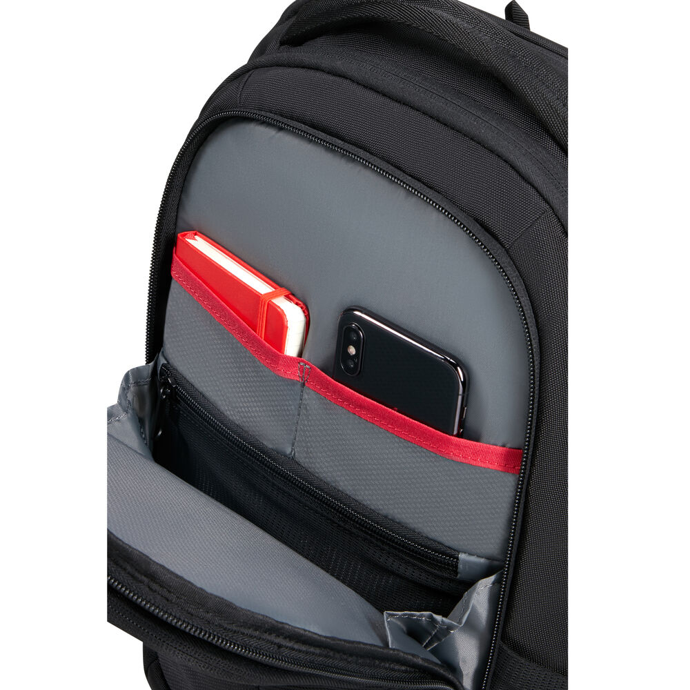 Schwarzer Rucksack mit offener Tasche. Ein rotes Notizbuch und ein schwarzes Smartphone sind darin. Grauer Innenraum und rote Zierleisten sind sichtbar.