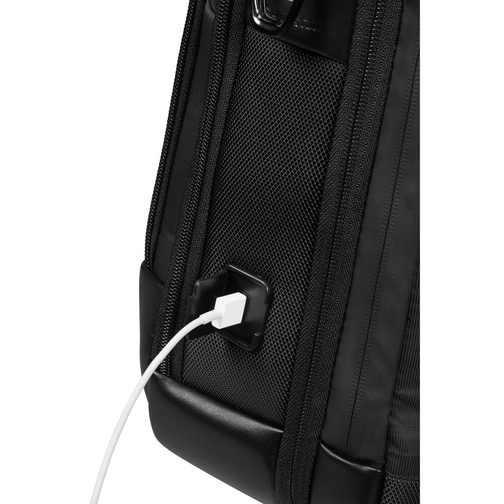 Primo piano di uno zaino nero con un cavo di ricarica bianco collegato a una porta. La porta è quadrata e nera.