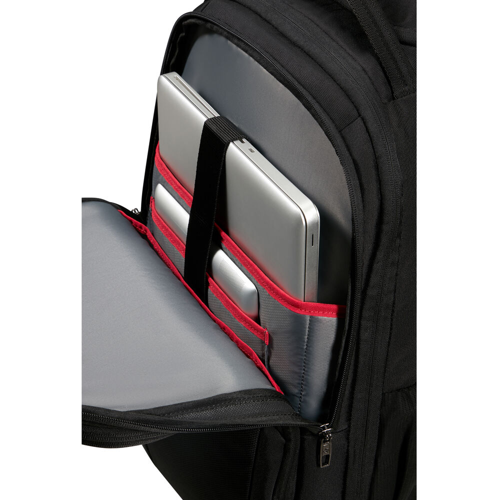 Sac à dos noir avec compartiment ouvert. À l'intérieur, des ordinateurs portables argentés et un petit appareil sont rangés dans des poches bordées de rouge.
