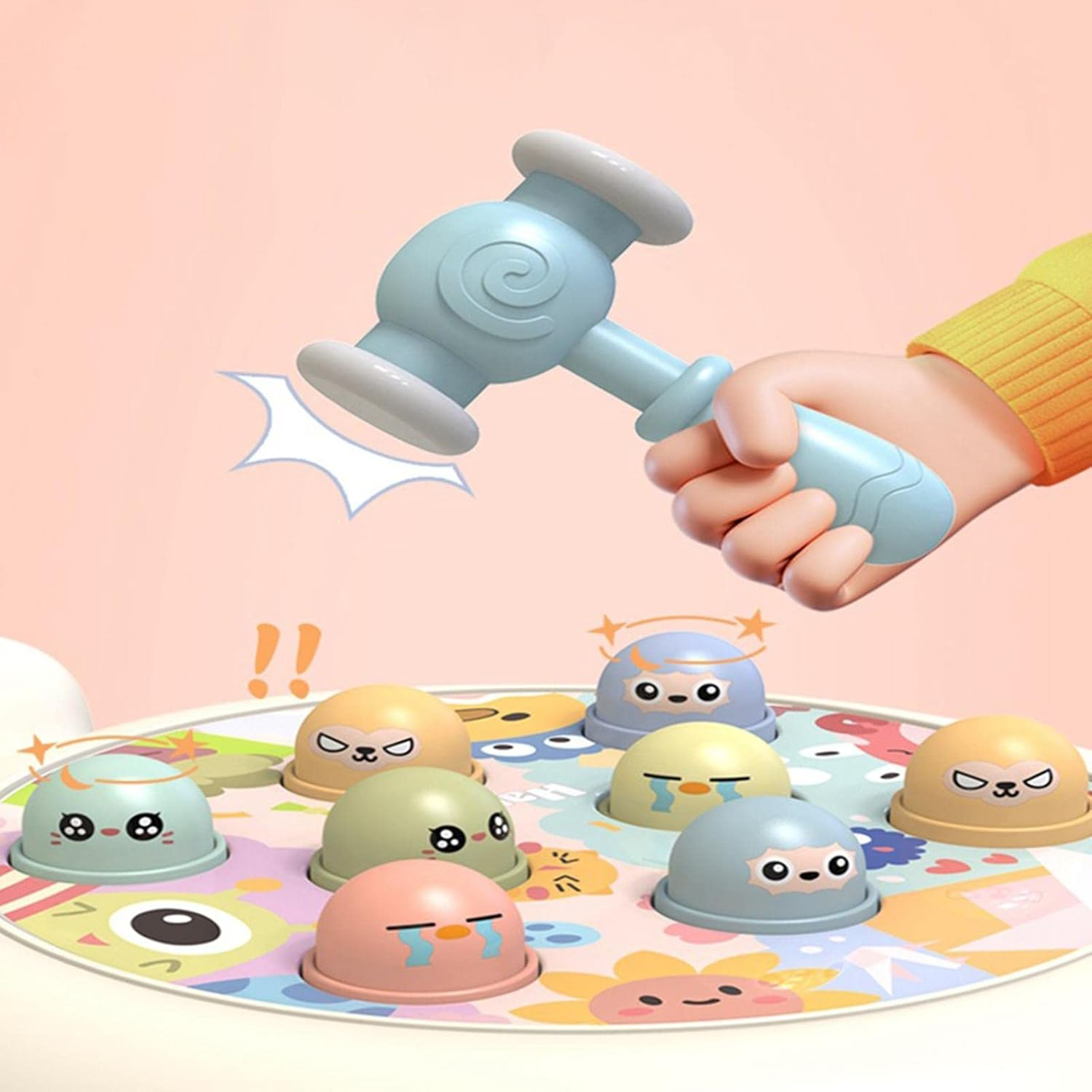 Eine Kinderhand hält einen blauen Hammer über einem farbenfrohen Spiel mit Cartoon-Tiergesichtern. Der Hintergrund ist hellrosa.