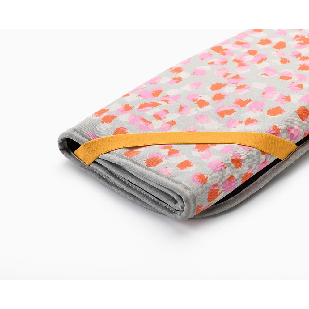 Una tela plegada estampada. Tiene manchas rosas y naranjas sobre un fondo gris. Una banda elástica naranja lo asegura.