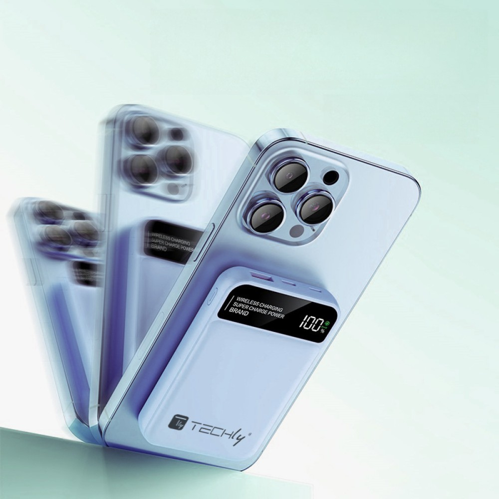 Un iPhone azzurro con un caricabatterie wireless collegato. Il caricabatterie mostra il 100%. Altri telefoni sono sfocati sullo sfondo.
