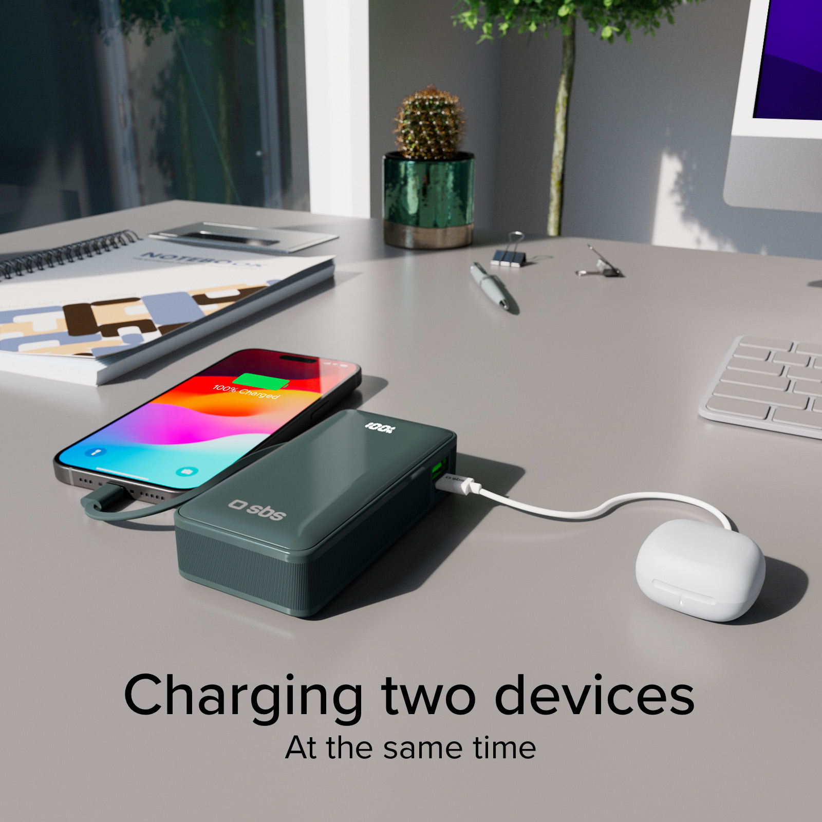 Un telefono e un power bank si ricaricano su una scrivania. Il telefono è al 100% e anche il power bank è al 100%.
