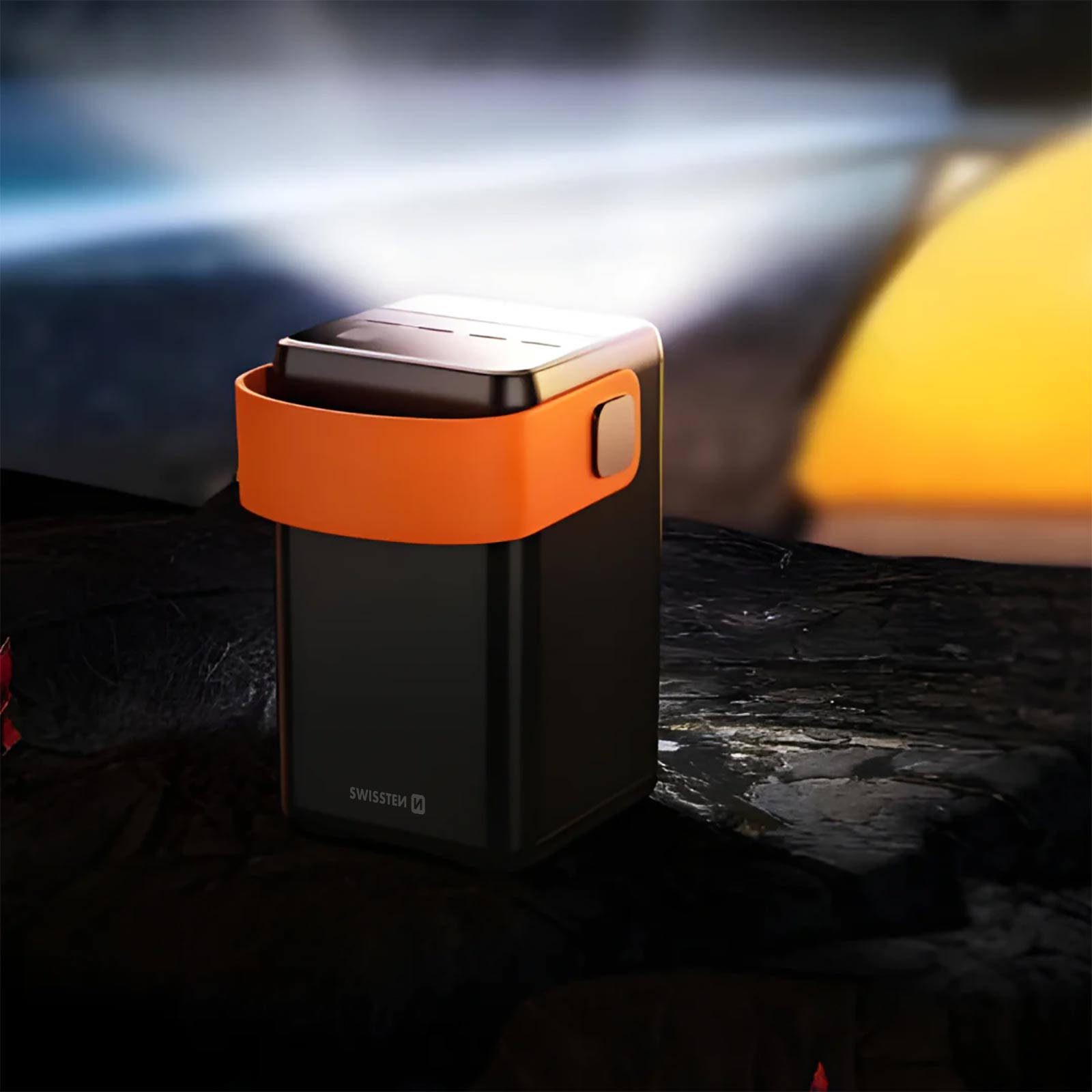 Una luce portatile nera e arancione. La luce brilla dall'alto. Lo sfondo è scuro e sfocato.