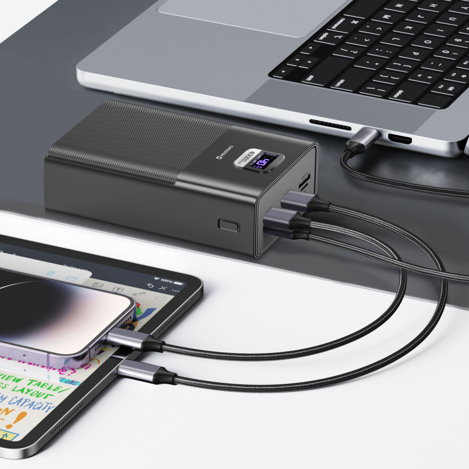 Un laptop, un power bank, un tablet e un telefono sono collegati. I cavi collegano i dispositivi per la ricarica. Il power bank visualizza 40.