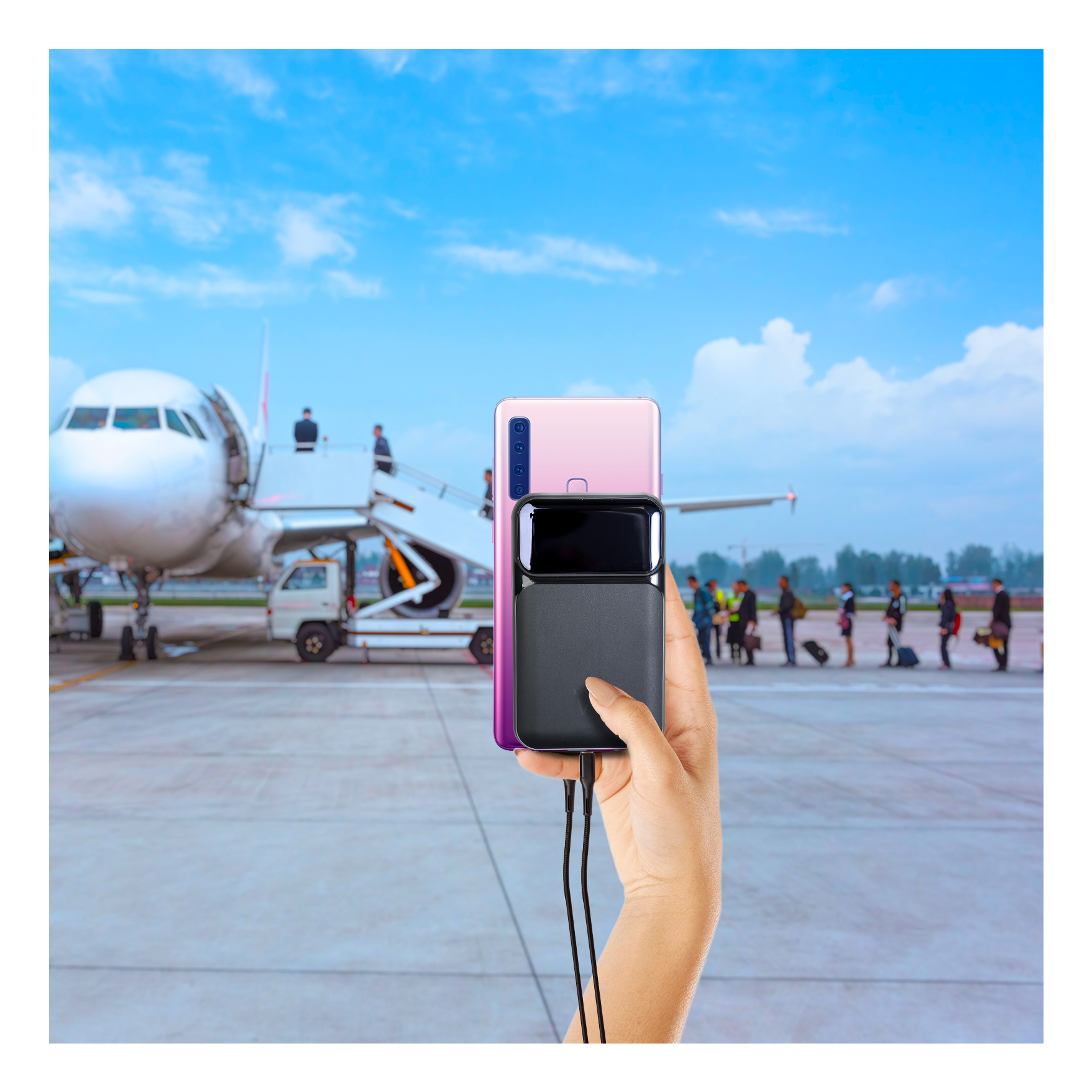 Mano che tiene un power bank e un telefono su sfondo aeroporto. Aereo, passeggeri e cielo blu sullo sfondo.