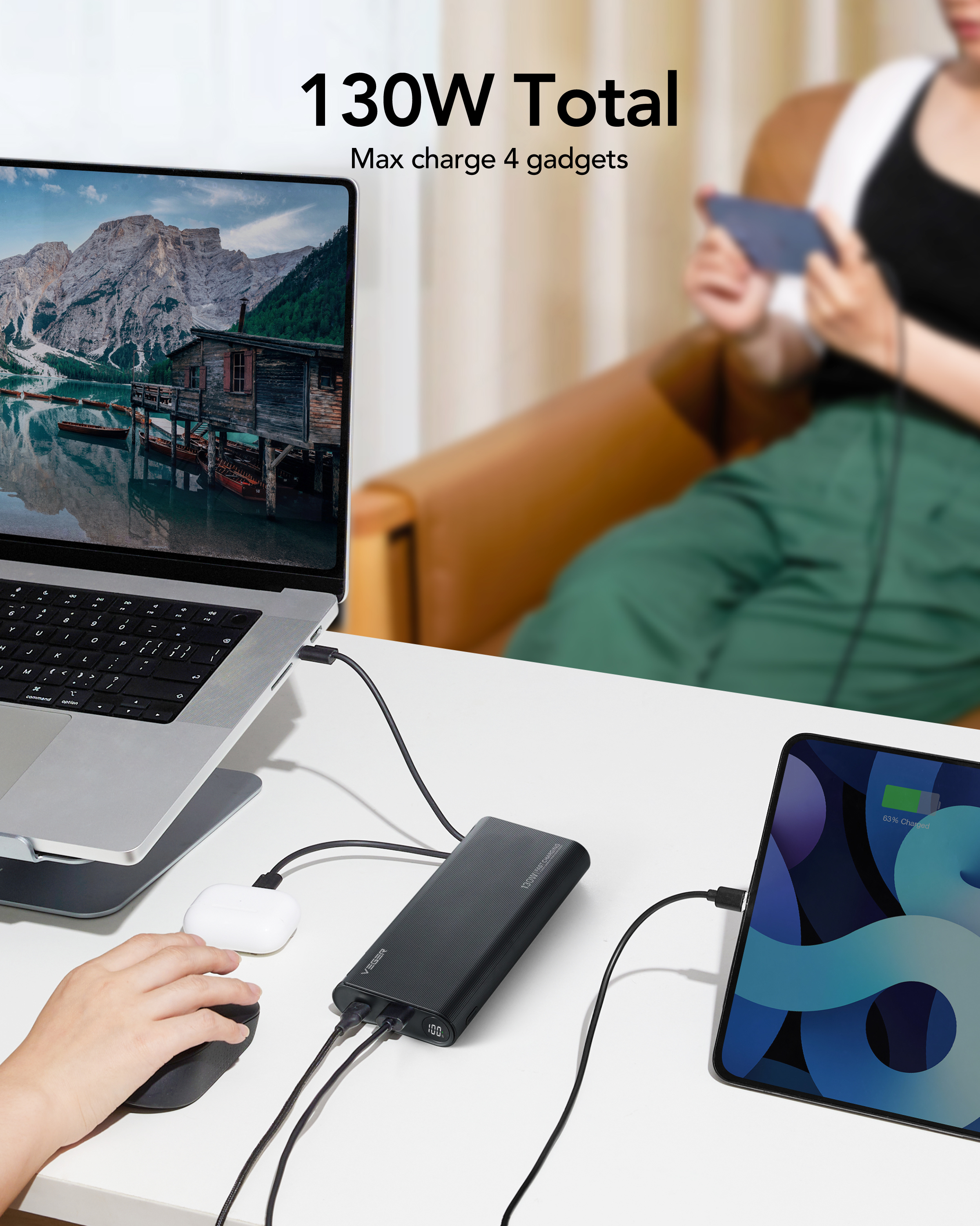 Laptop, tablet e AirPods in carica da un power bank. Una persona usa il mouse.