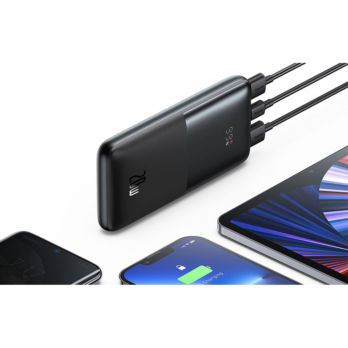 Un power bank nero che carica tre dispositivi: un telefono, un altro telefono e un tablet. Il telefono mostra 7:17, uno in carica.