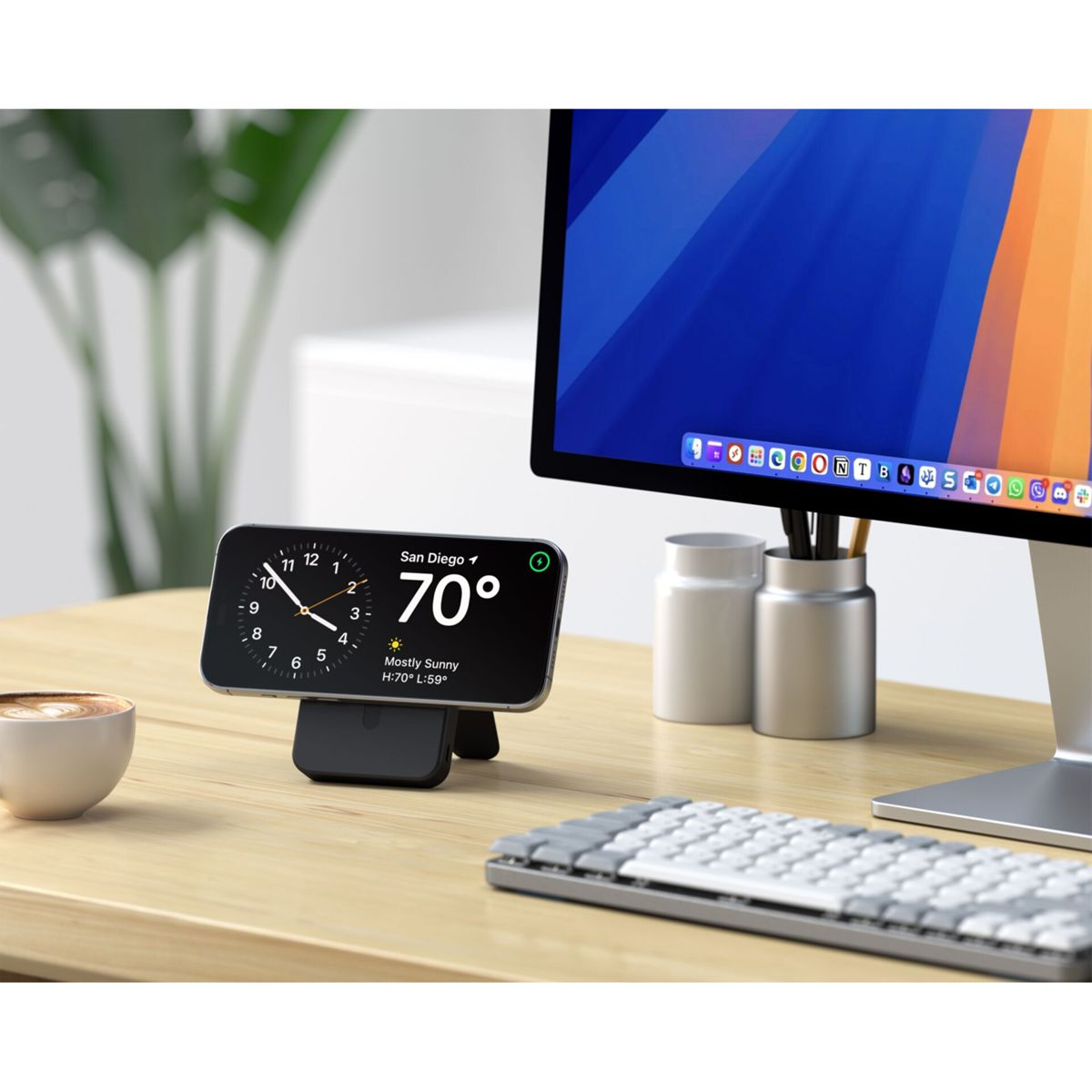 Un telefono che mostra l'ora e il meteo è su una scrivania. Sono presenti anche un monitor del computer, una tastiera e una tazza di caffè.