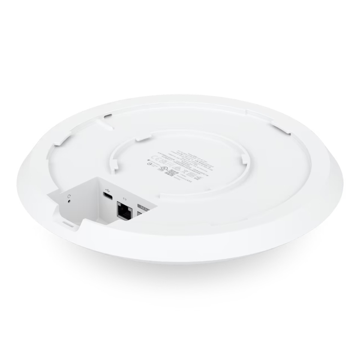 Un dispositivo blanco y circular, probablemente un punto de acceso a la red, visto desde abajo. Tiene puertos, etiquetas y un área empotrada.