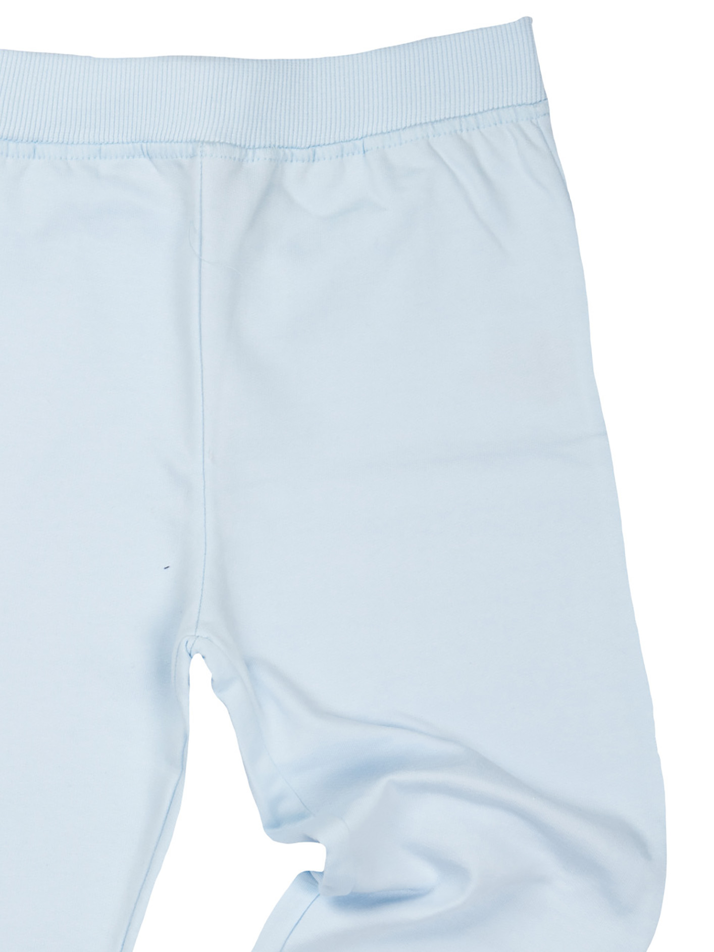 Nahaufnahme einer hellblauen Hose. Der obere Teil hat einen gerippten Bund, der Stoff ist glatt und weist feine Falten auf.