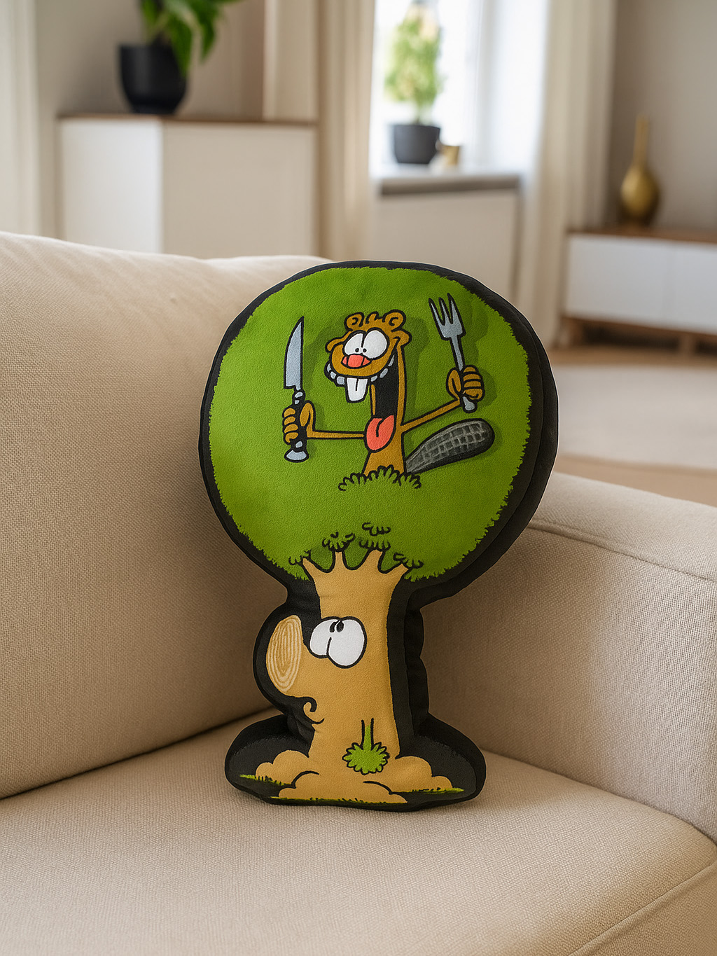 Ein baumförmiges Kissen auf einem beigen Sofa. Der Baum hat einen Biber mit Messer und Gabel. Hintergrund: Wohnzimmer.