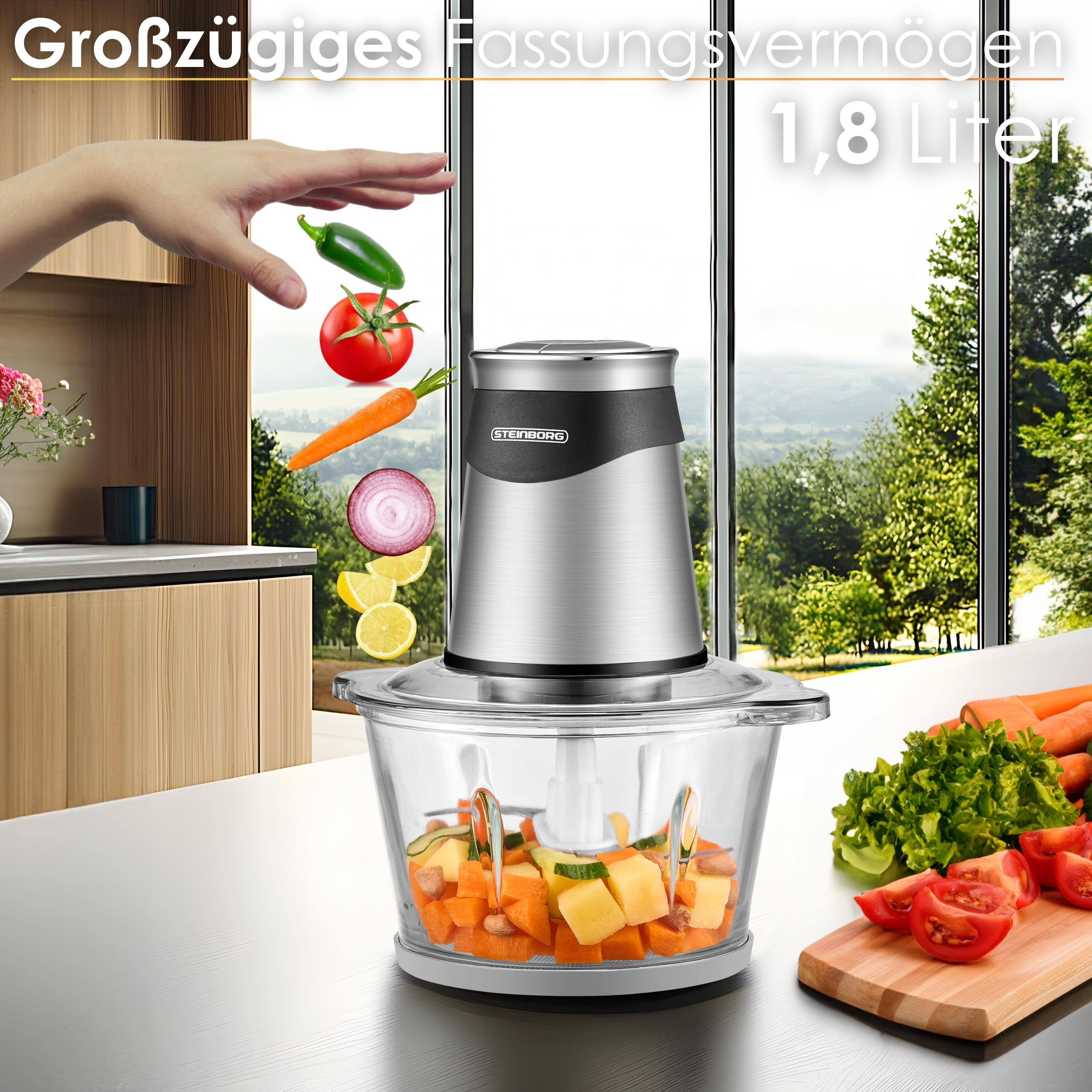 Ein Foodprozessor mit Gemüse, das hineinfällt. Der Hintergrund zeigt eine malerische Aussicht.