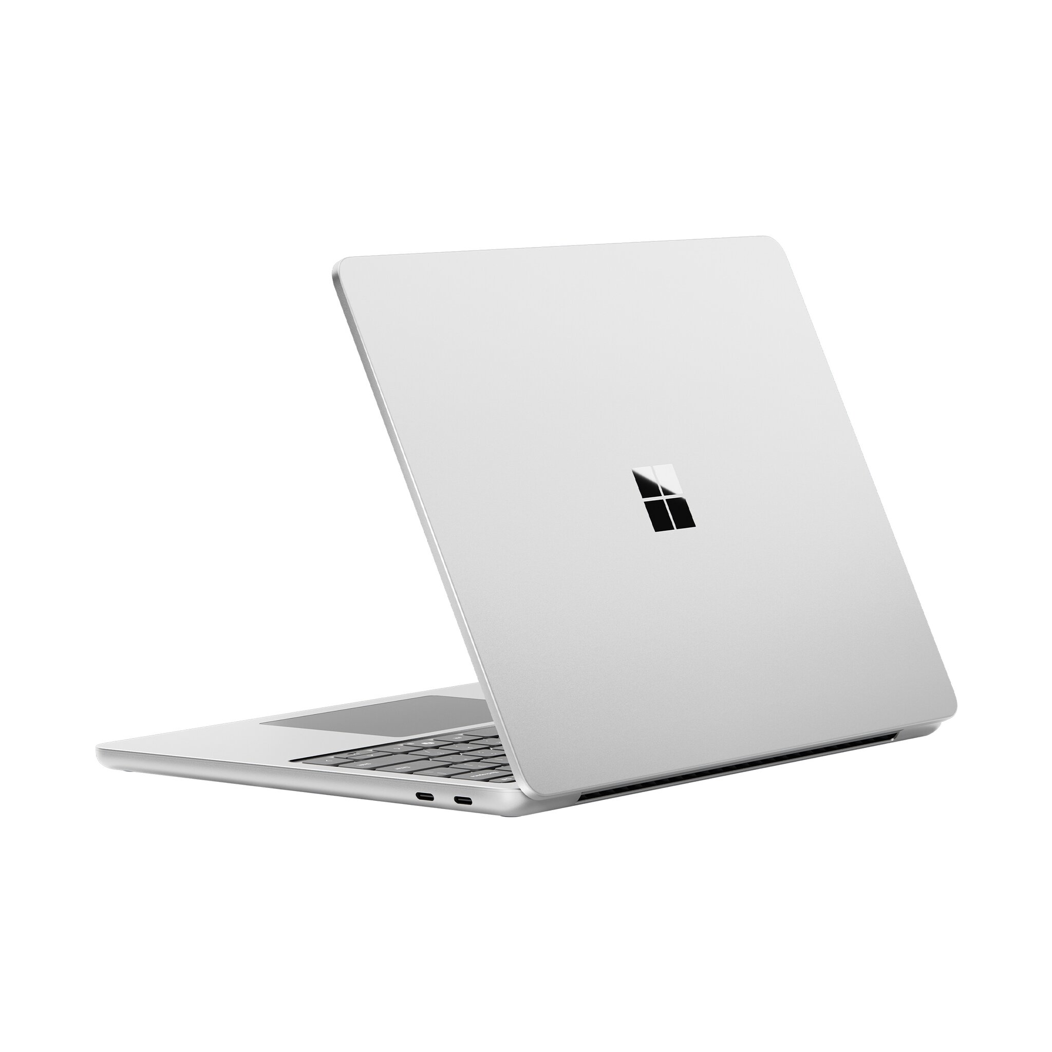 Un laptop argentato è aperto su una superficie bianca. Il logo Microsoft è visibile sul coperchio. La tastiera è in primo piano.