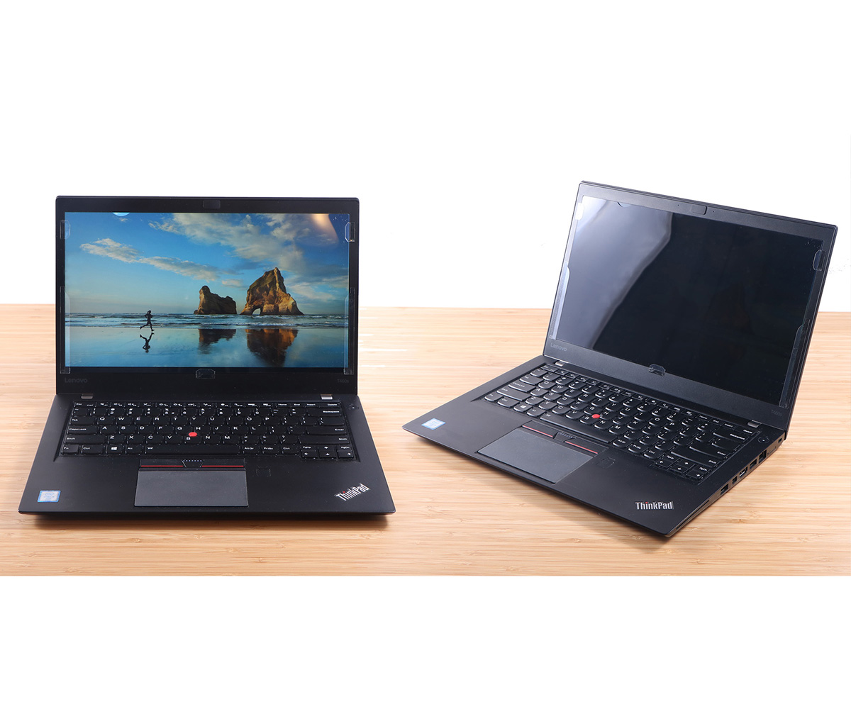 Dwa czarne laptopy ThinkPad na jasnej drewnianej powierzchni. Jeden wyświetla scenę plażową; drugi ma pusty ekran.