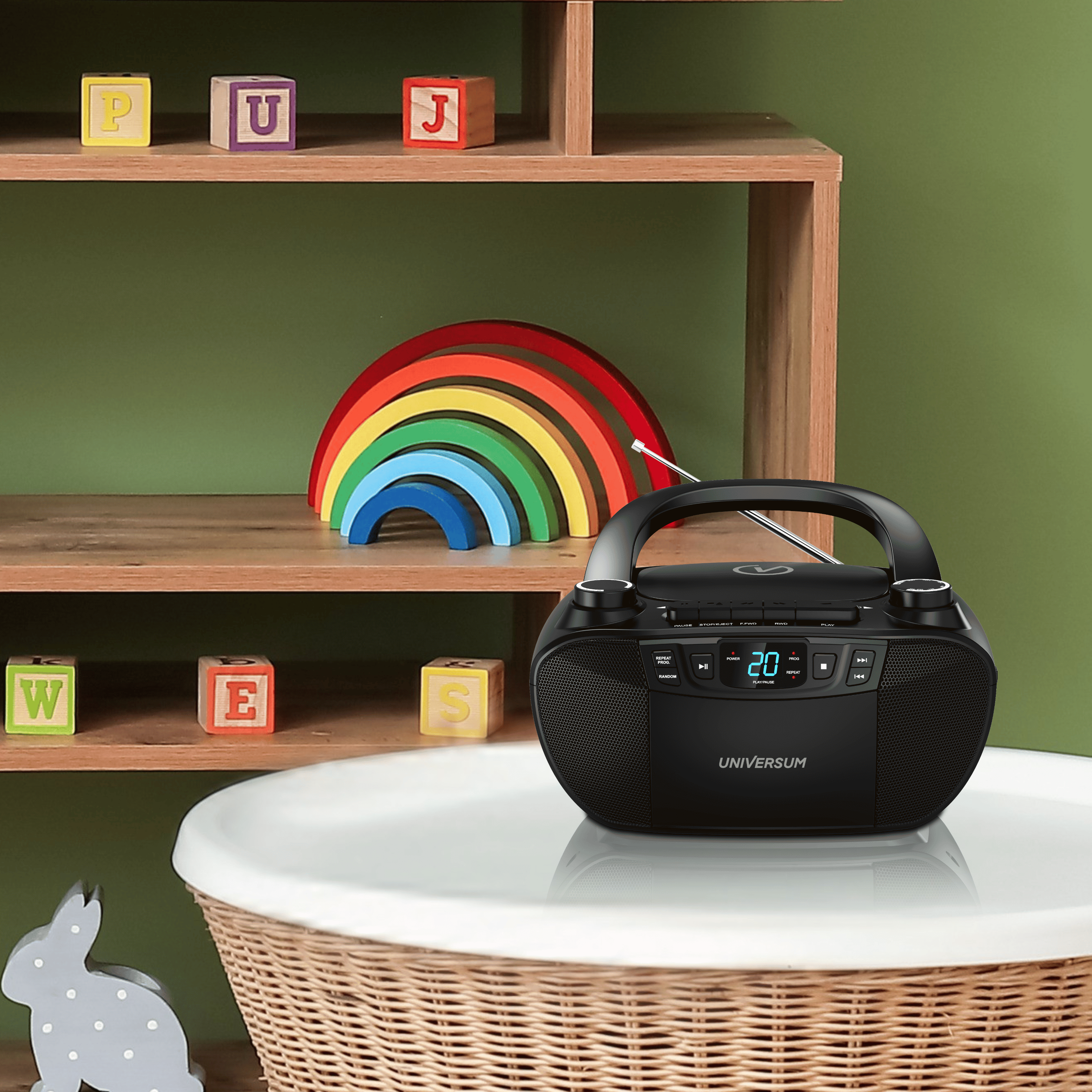 Ein schwarzer Ghettoblaster steht auf einem Tisch. Ein Regenbogen und Alphabetblöcke sind auf einem Regal.