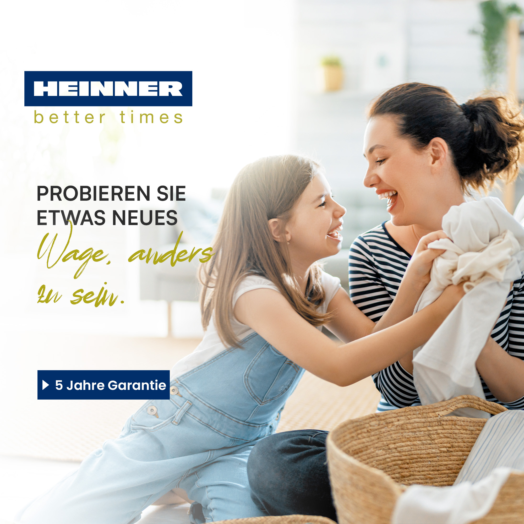 Eine Frau und ein Mädchen lachen und halten Kleidung in der Nähe eines Wäschekorbs. Text: 'HEINNER' und '5 Jahre Garantie'.