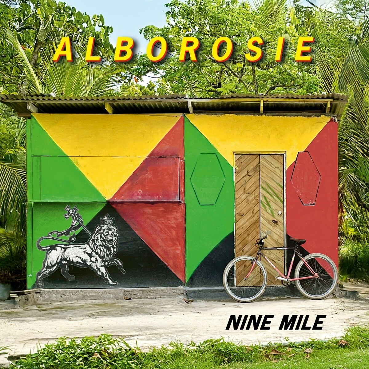 Un edificio colorato con un leone. Una bicicletta è appoggiata alla porta. I testi 'ALBOROSIE' e 'NINE MILE' sono visibili.
