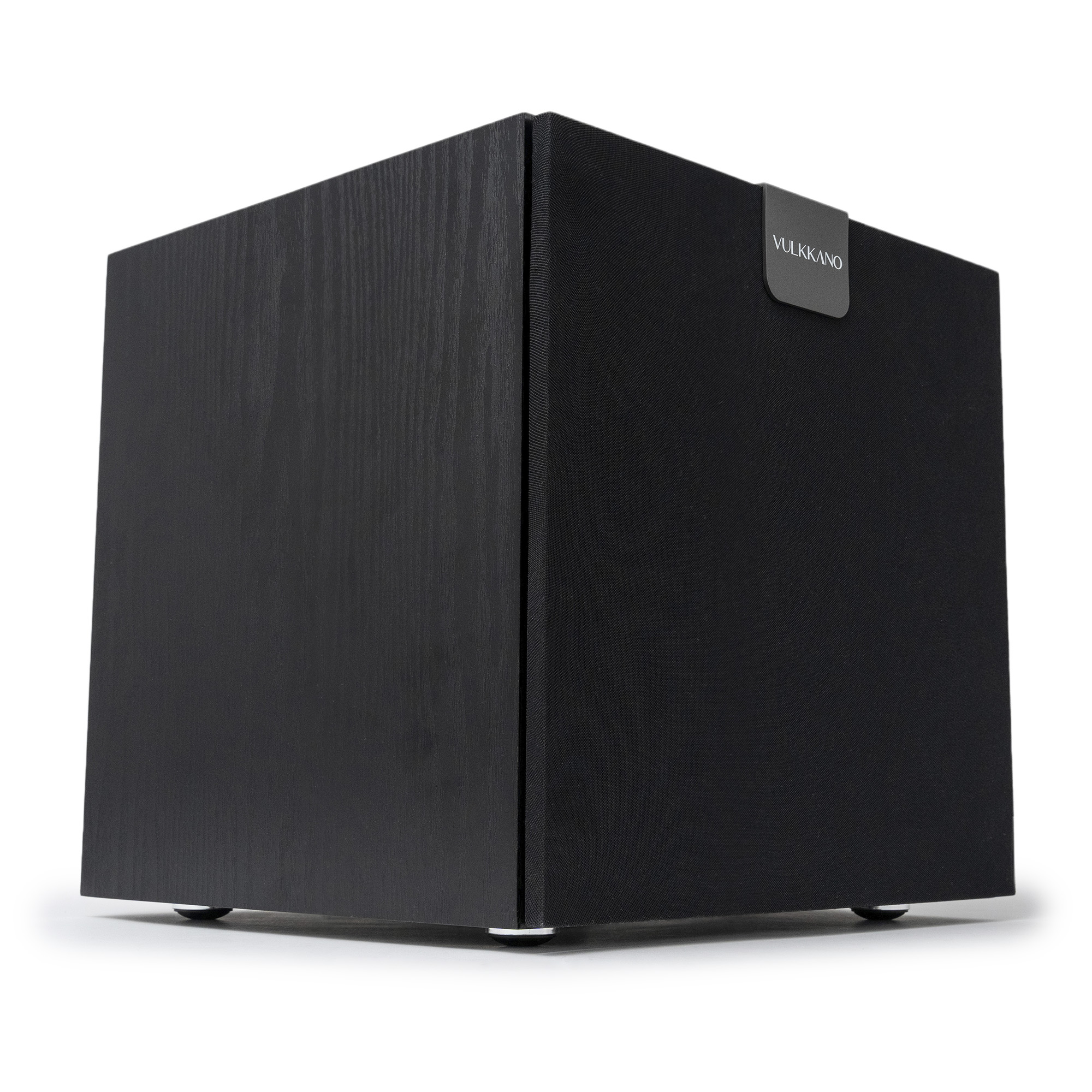 Un subwoofer nero con finitura effetto legno. La parola VULKANO è visibile. Poggia su una superficie bianca.