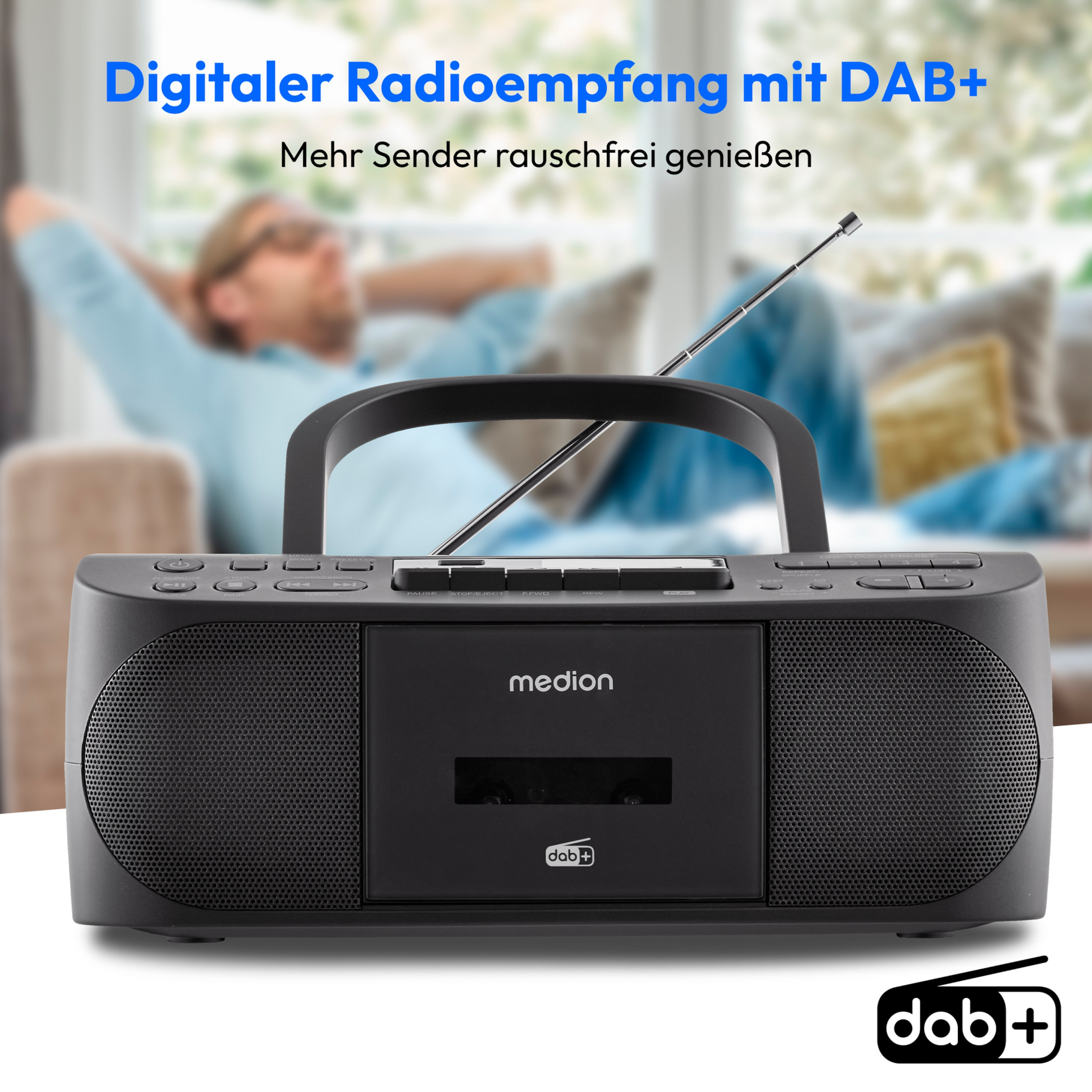 Ein schwarzes Radio mit Griff. Im Hintergrund liegt eine Person auf einem Sofa.