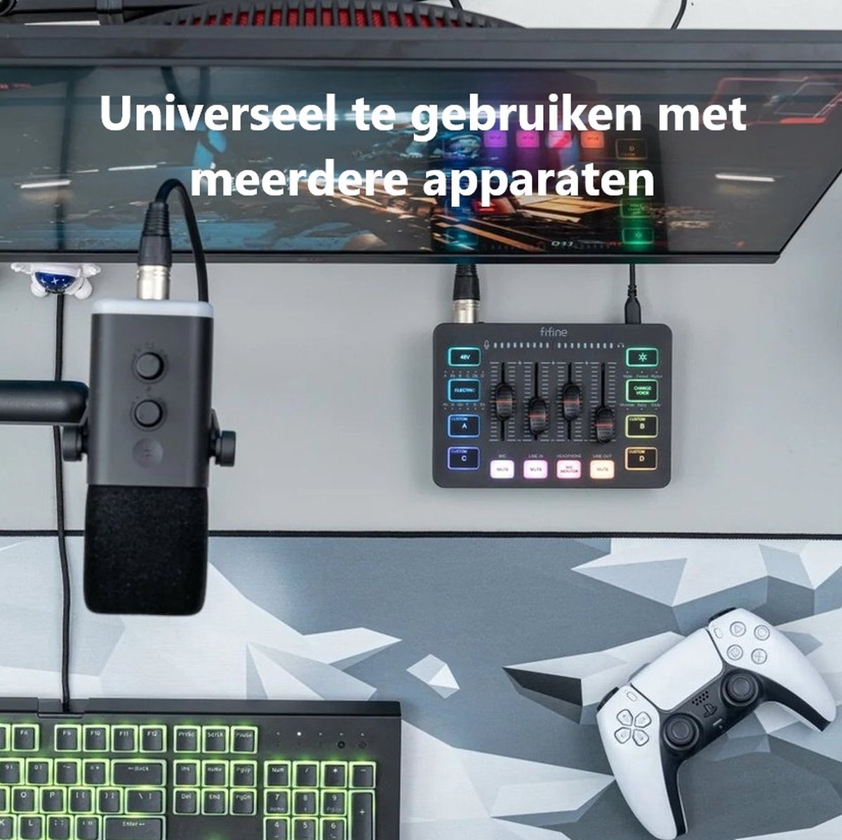 A gaming setup with microphone, mixer, keyboard, and a white controller. A monitor displays text: "Universally used with multiple devices"