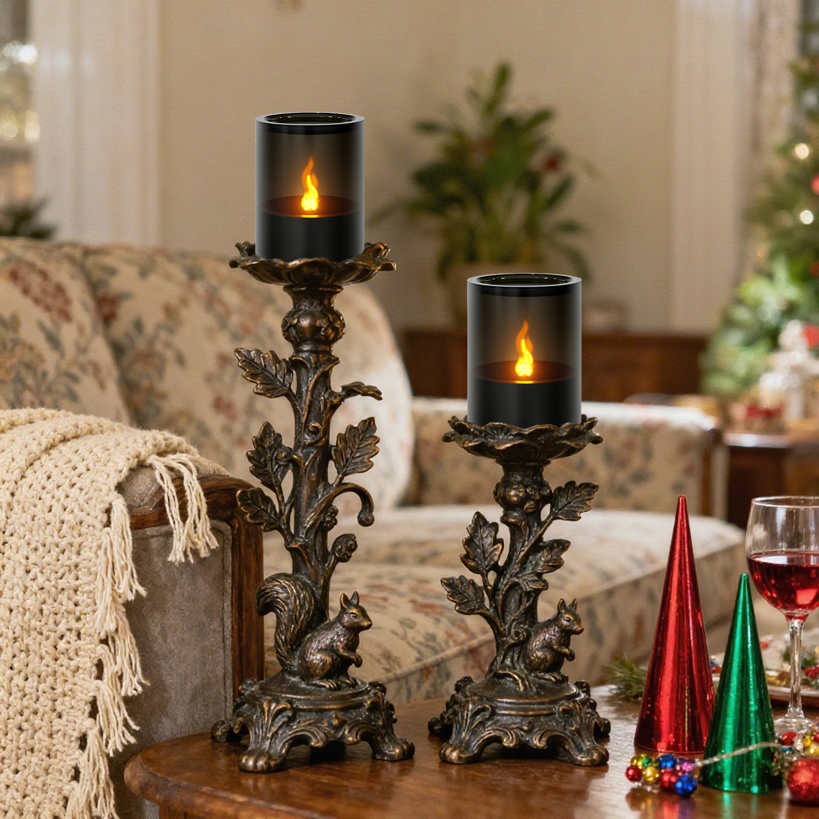 Zwei Kerzenhalter mit Eichhörnchensockel, Kerzen mit Flamme, rote und grüne Kegel, ein Glas Rotwein und ein Weihnachtsbaum.
