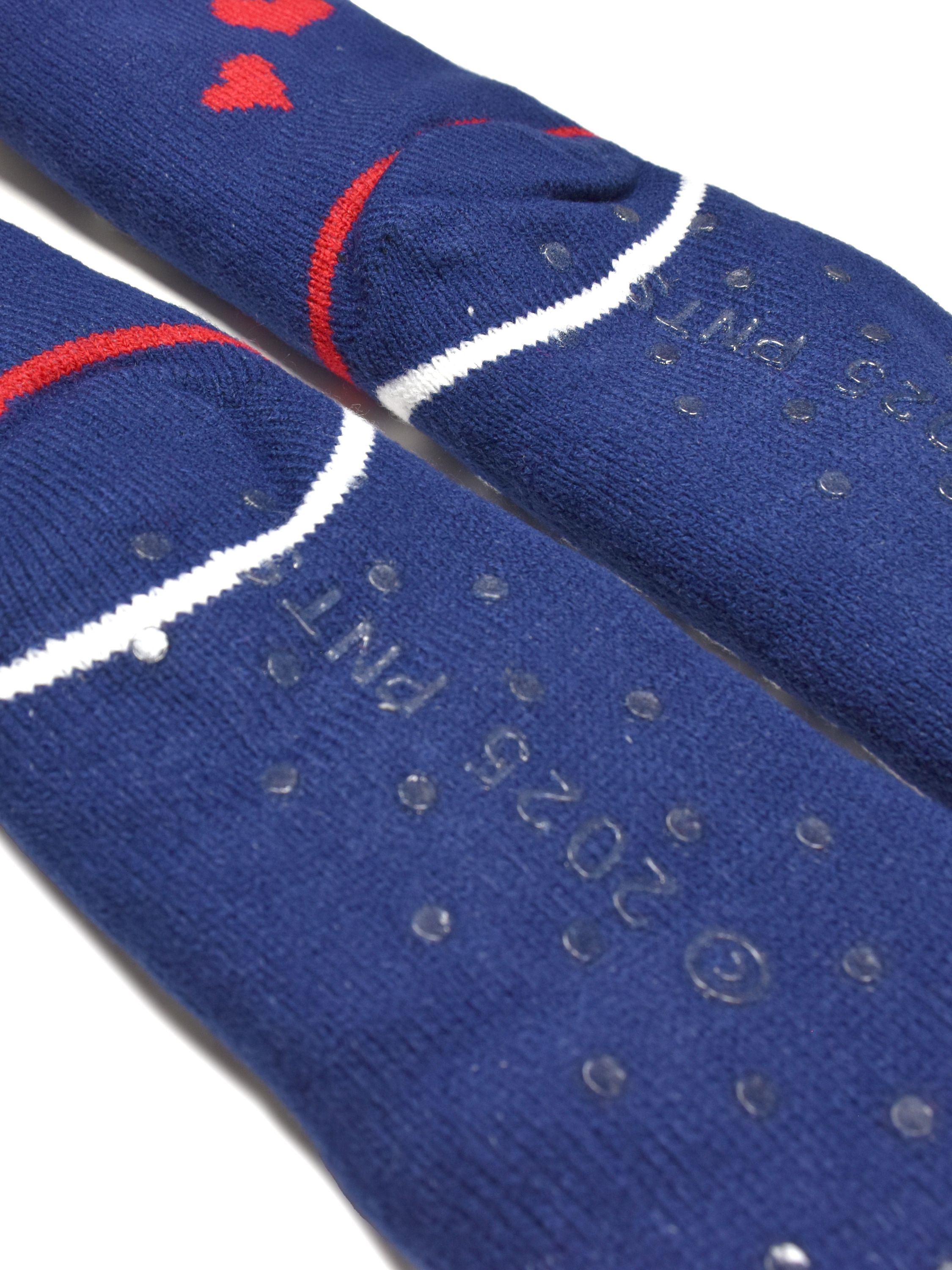 Nahaufnahme von blauen Socken mit roten Akzenten und Herzen. Anti-Rutsch-Punkte bedecken den Boden. Weißer Hintergrund.
