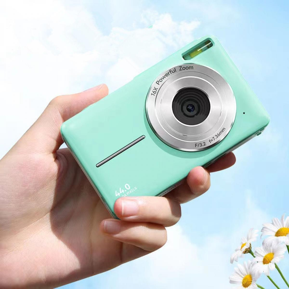 Eine Hand hält eine mintgrüne Kamera. Die Kamera hat ein silbernes Objektiv und der Hintergrund ist ein blauer Himmel mit weißen Blumen.
