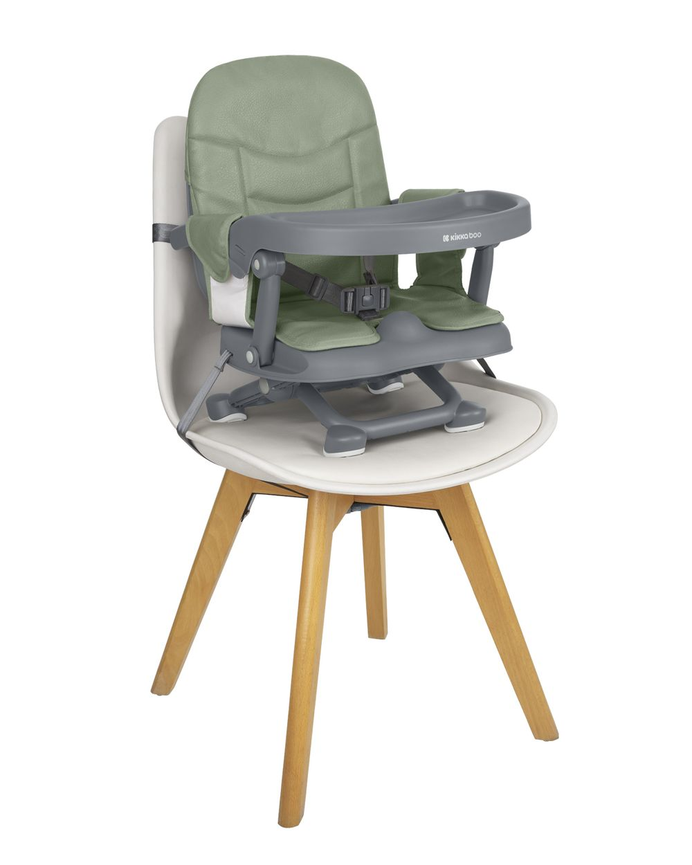 Una trona para bebés se encuentra sobre una silla blanca con patas de madera. La trona es verde y gris con una bandeja y correas de seguridad.
