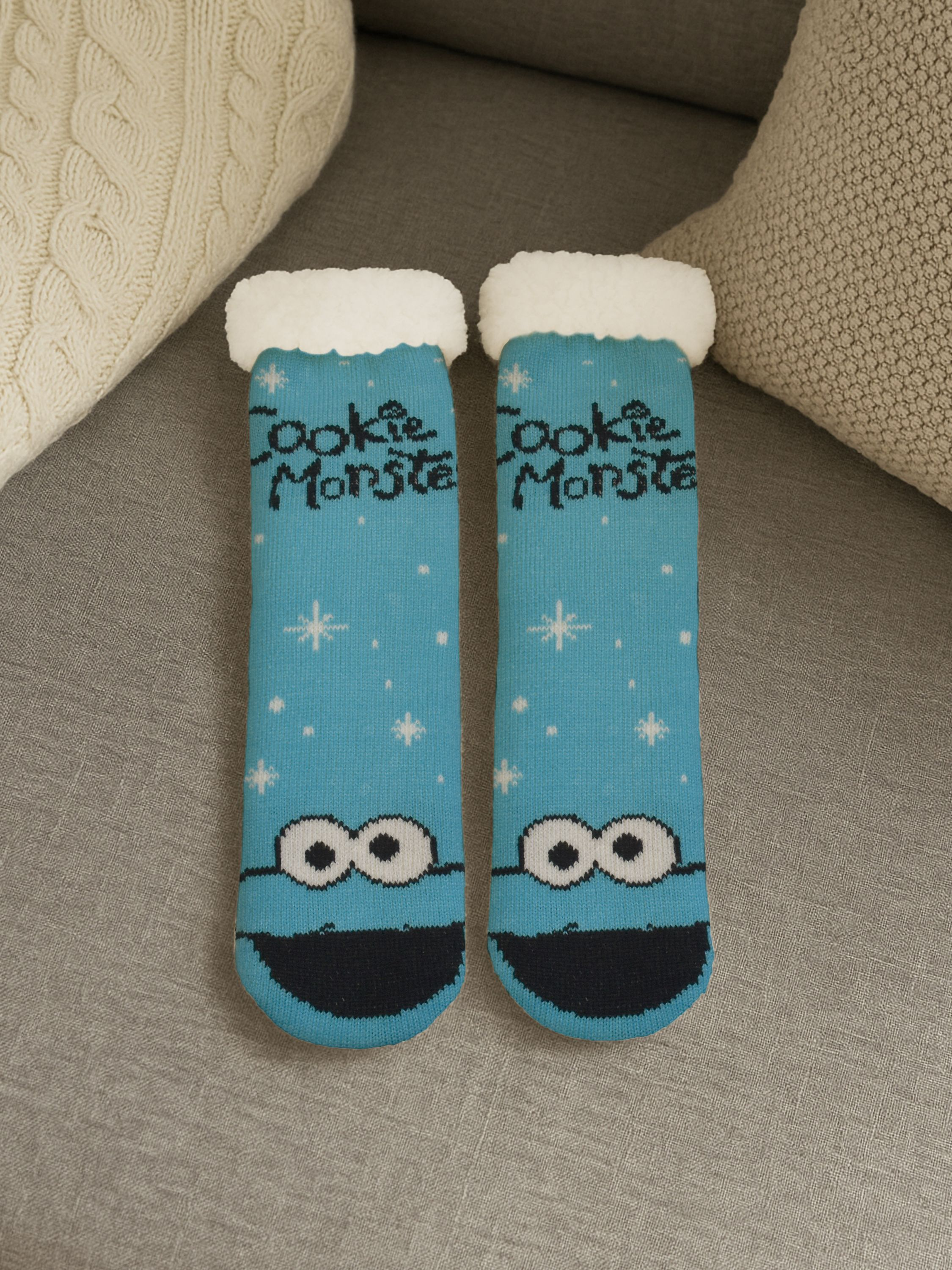 Paar Cookie Monster Socken auf grauer Oberfläche. Blaue Socken mit weißem Rand und Cookie Monster Gesicht.