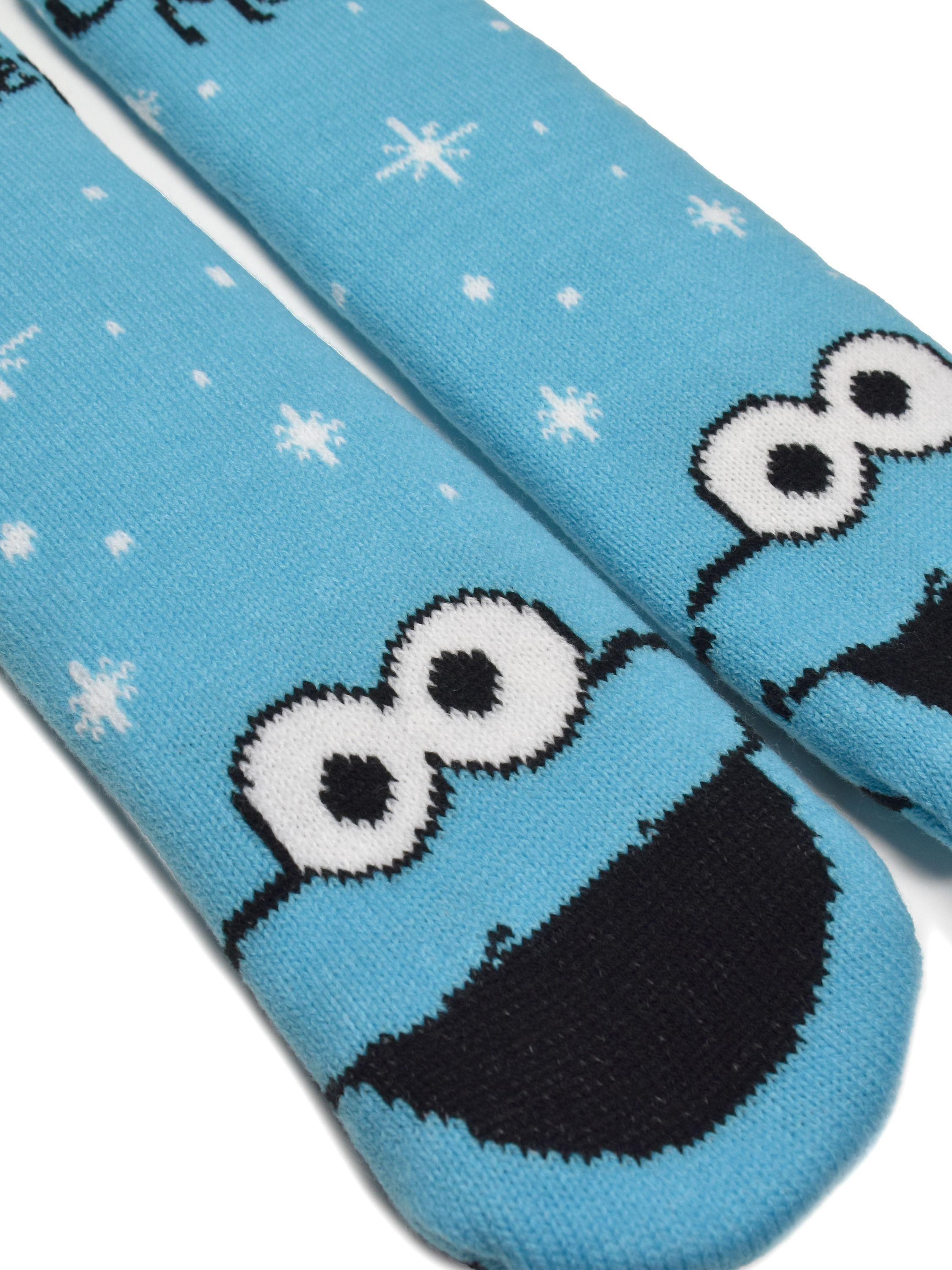Zwei blaue Socken mit Krümelmonster-Gesichtern. Schneeflockenmuster und weißer Hintergrund sind sichtbar.