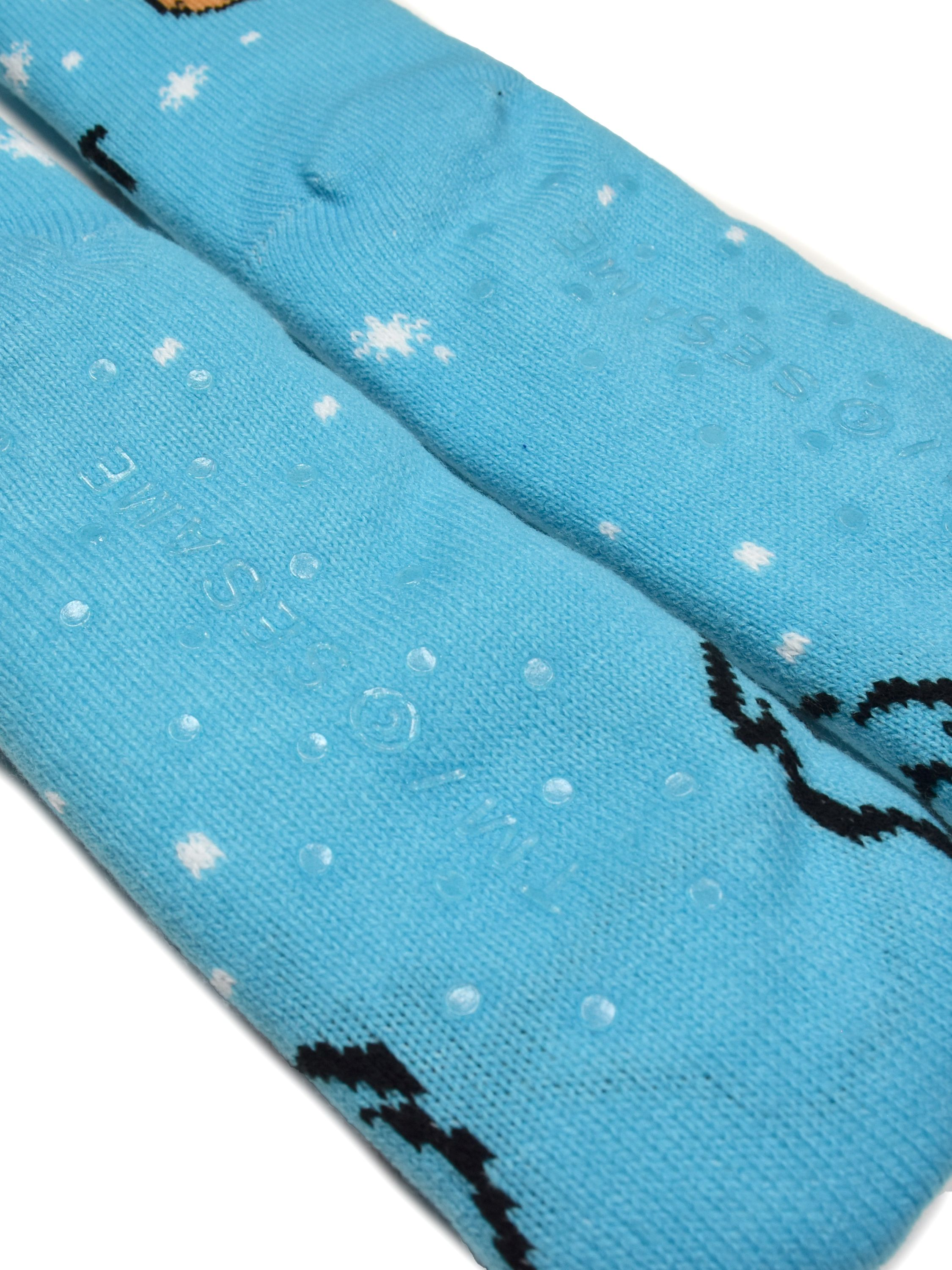 Zwei blaue Socken mit weißen Schneeflockenmustern und Grip-Punkten. Ein schwarzes Design ist im Zehenbereich sichtbar.