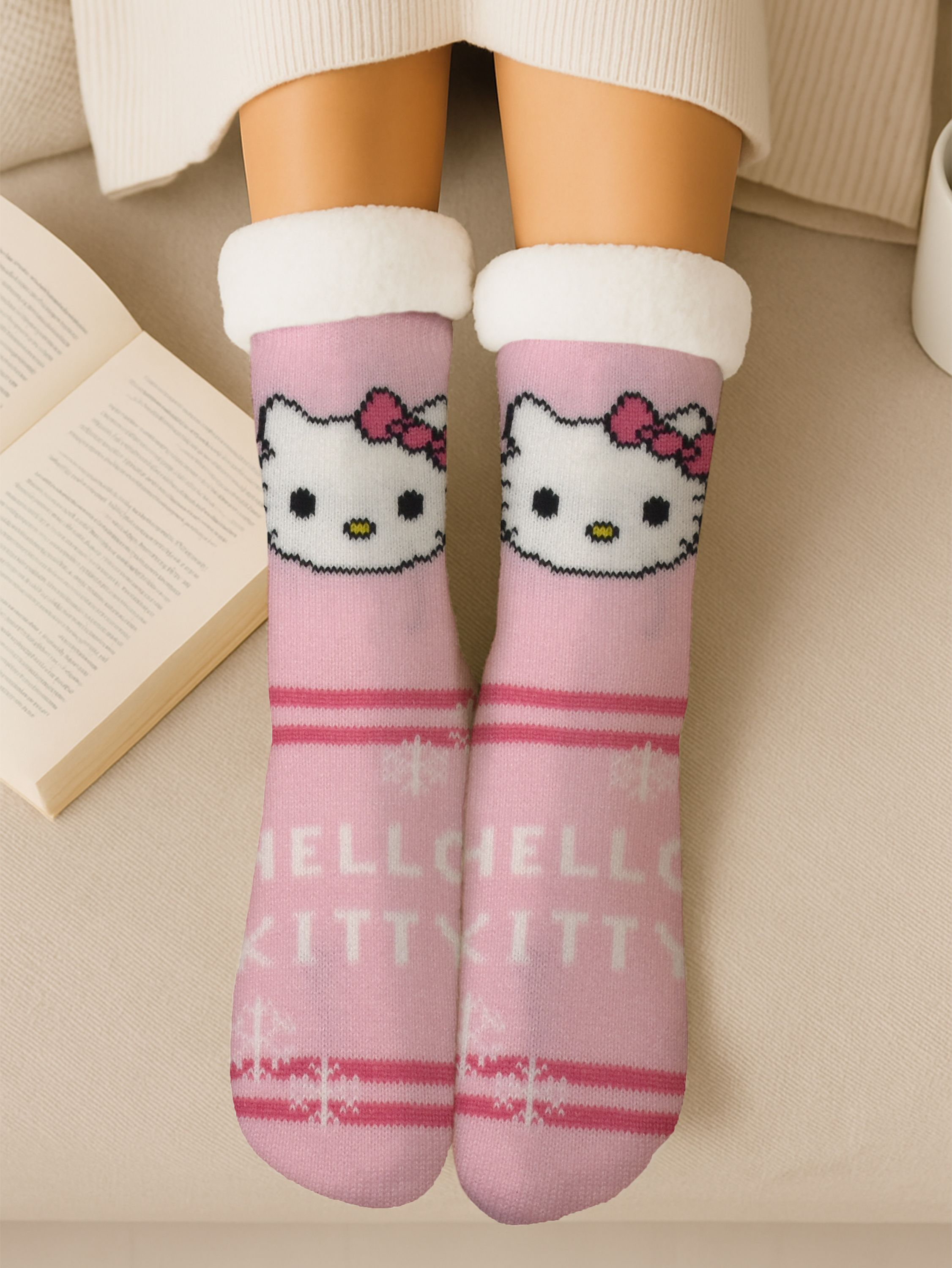 Rosa Hello Kitty Socken an Beinen, offenes Buch, weißer Pullover, beigefarbene Oberfläche.