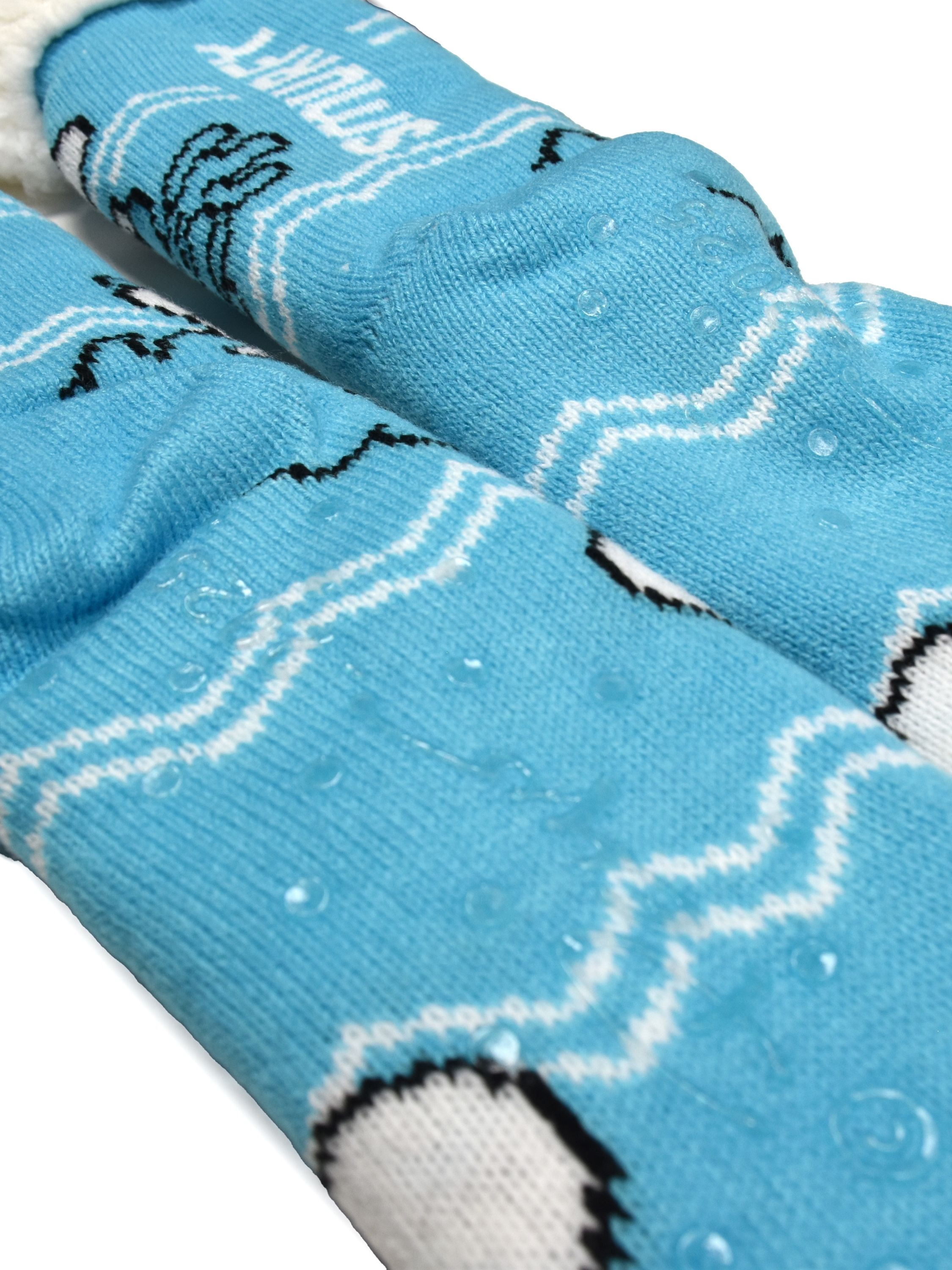 Nahaufnahme von blauen Socken mit weißen Zickzacklinien und schwarzen Akzenten. Klare Griffe sind sichtbar. Weiches, weißes Material innen.