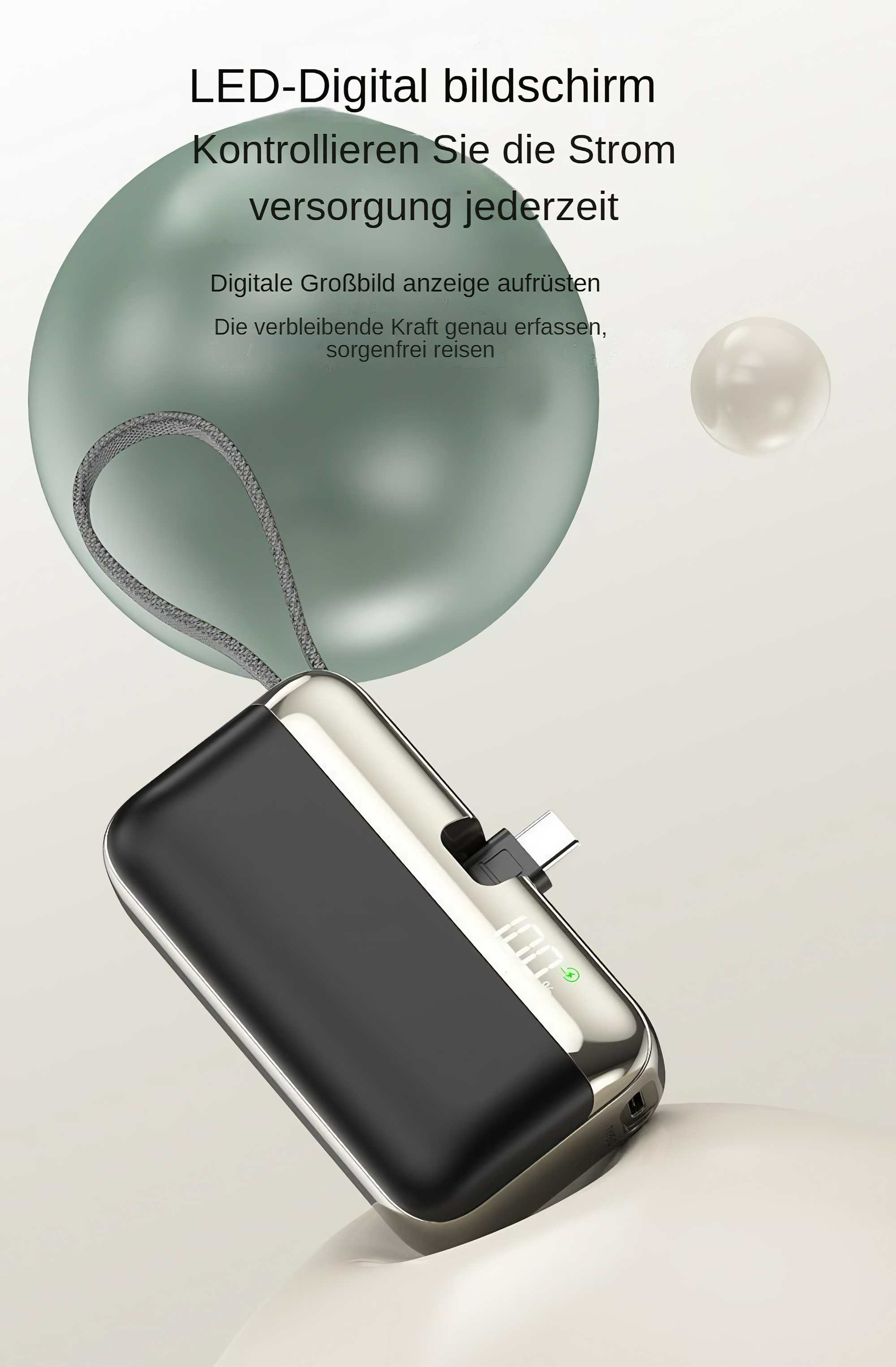 Eine Powerbank mit schwarzem und silbernem Design. Ein grüner Kreis zeigt die Ladung an. Texte auf Deutsch sind im Hintergrund sichtbar.