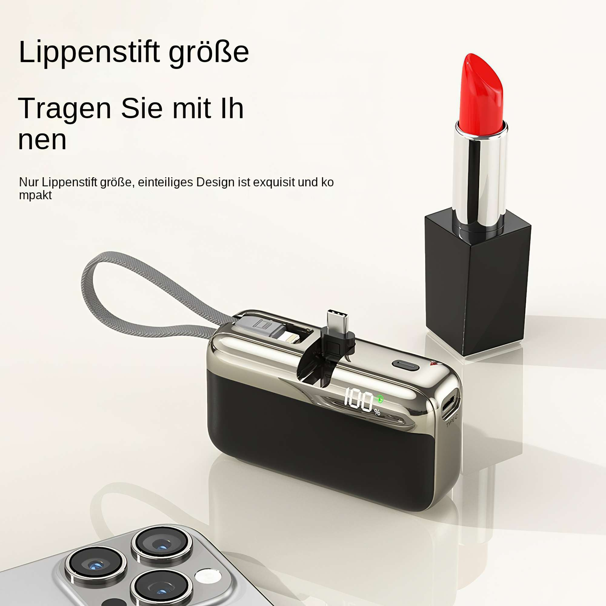 Ein roter Lippenstift steht neben einer schwarzen und silbernen Powerbank, mit einem Telefon unten links. Die Bank zeigt 100%.