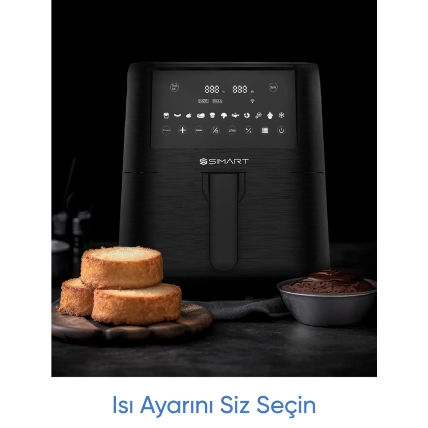 Dijital ekranlı siyah bir hava fritözü ve ahşap bir tahta üzerinde üç yuvarlak pişmiş ürün. Küçük bir kase çikolatalı kek.