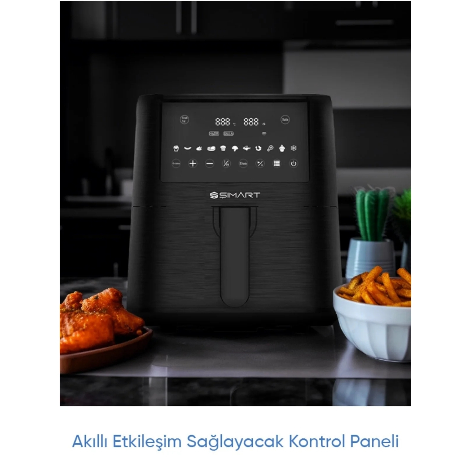 Dijital ekranlı siyah bir fritöz, tavuk kanatları ve patates kızartması. Arka planda bir kaktüs ve mutfak eşyaları.