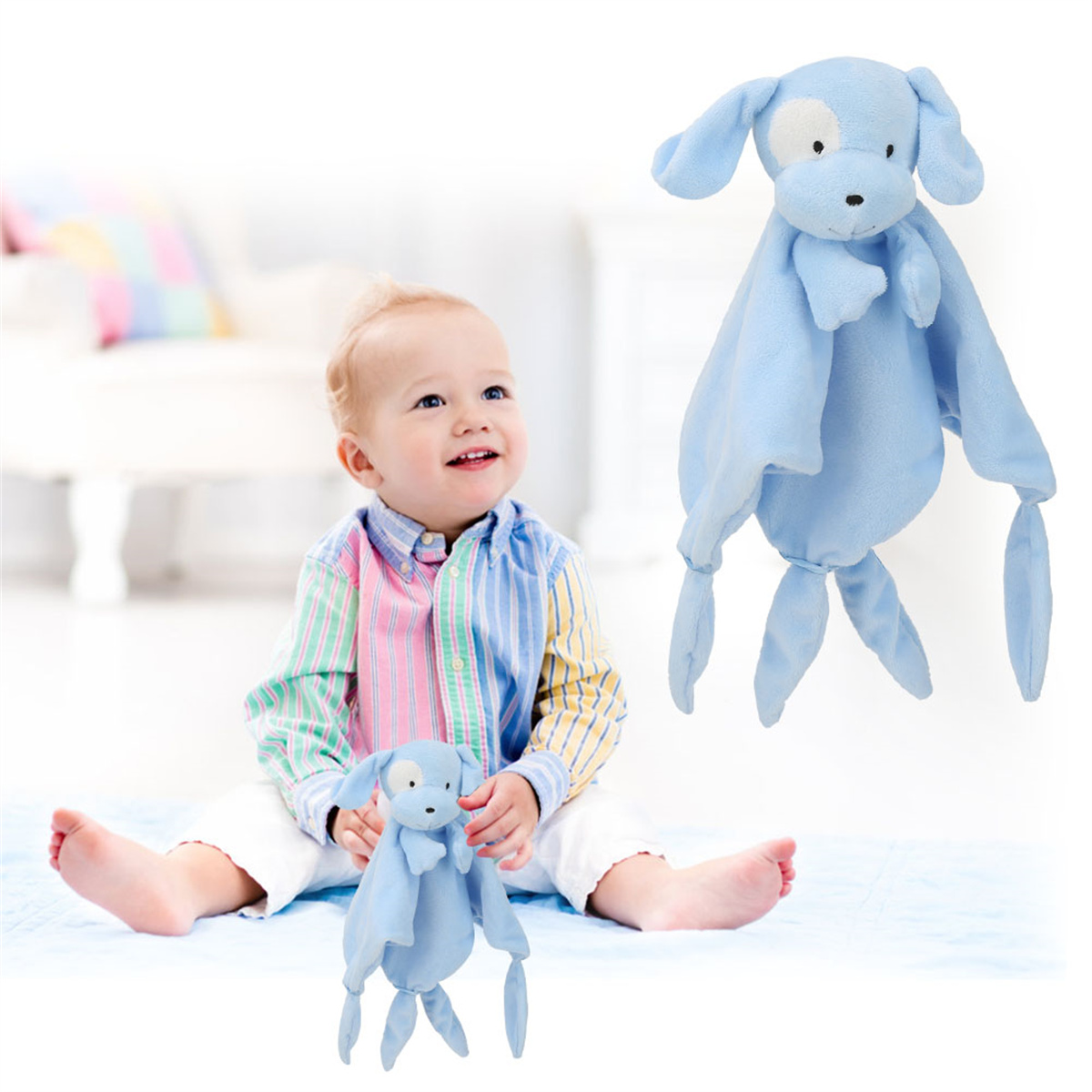 Ein Baby lächelt und hält ein blaues Hundespielzeug. Ein weiteres Hundespielzeug schwebt. Das Baby trägt ein buntes Hemd und weiße Hosen.