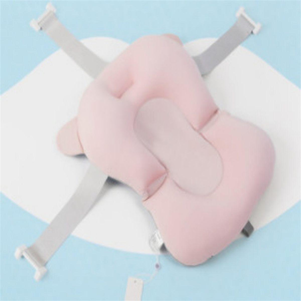 Ein rosa Baby-Badestützkissen mit grauen Gurten auf einer blau-weißen Oberfläche.