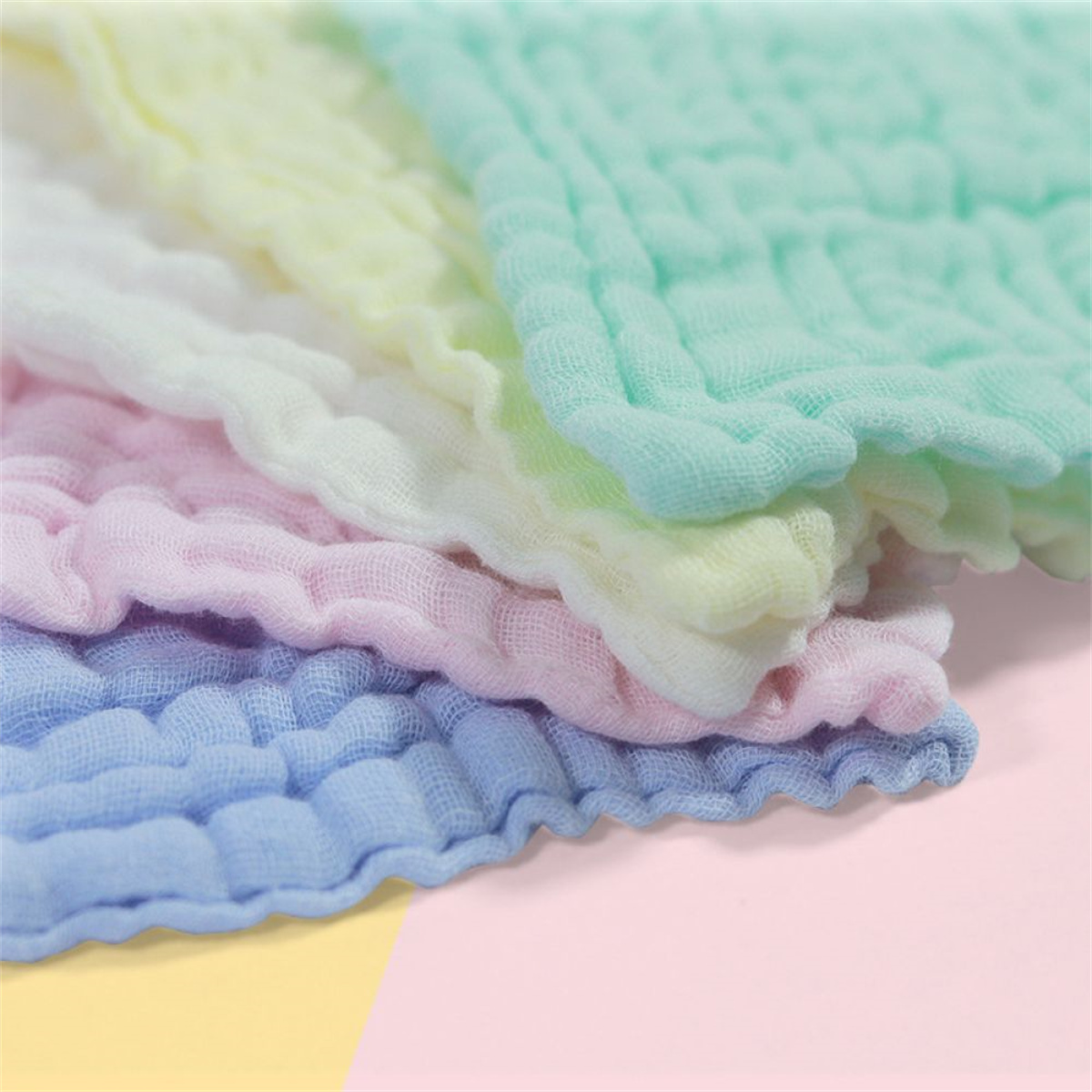 Nahaufnahme von Stoffquadraten in Pastellfarben: Blau, Rosa, Weiß, Gelb und Grün. Der Stoff hat ein strukturiertes, zerknittertes Aussehen.