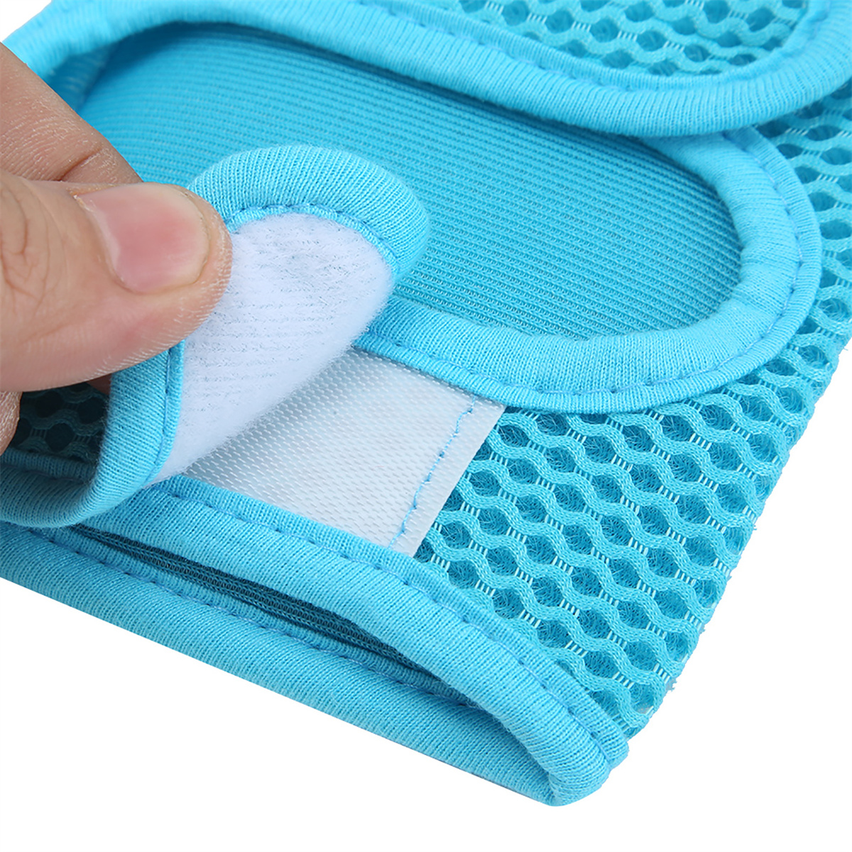 Eine Hand öffnet einen blauen Netzstoff mit weißem Klettverschluss. Der Stoff hat einen blauen Rand. Der Hintergrund ist weiß.