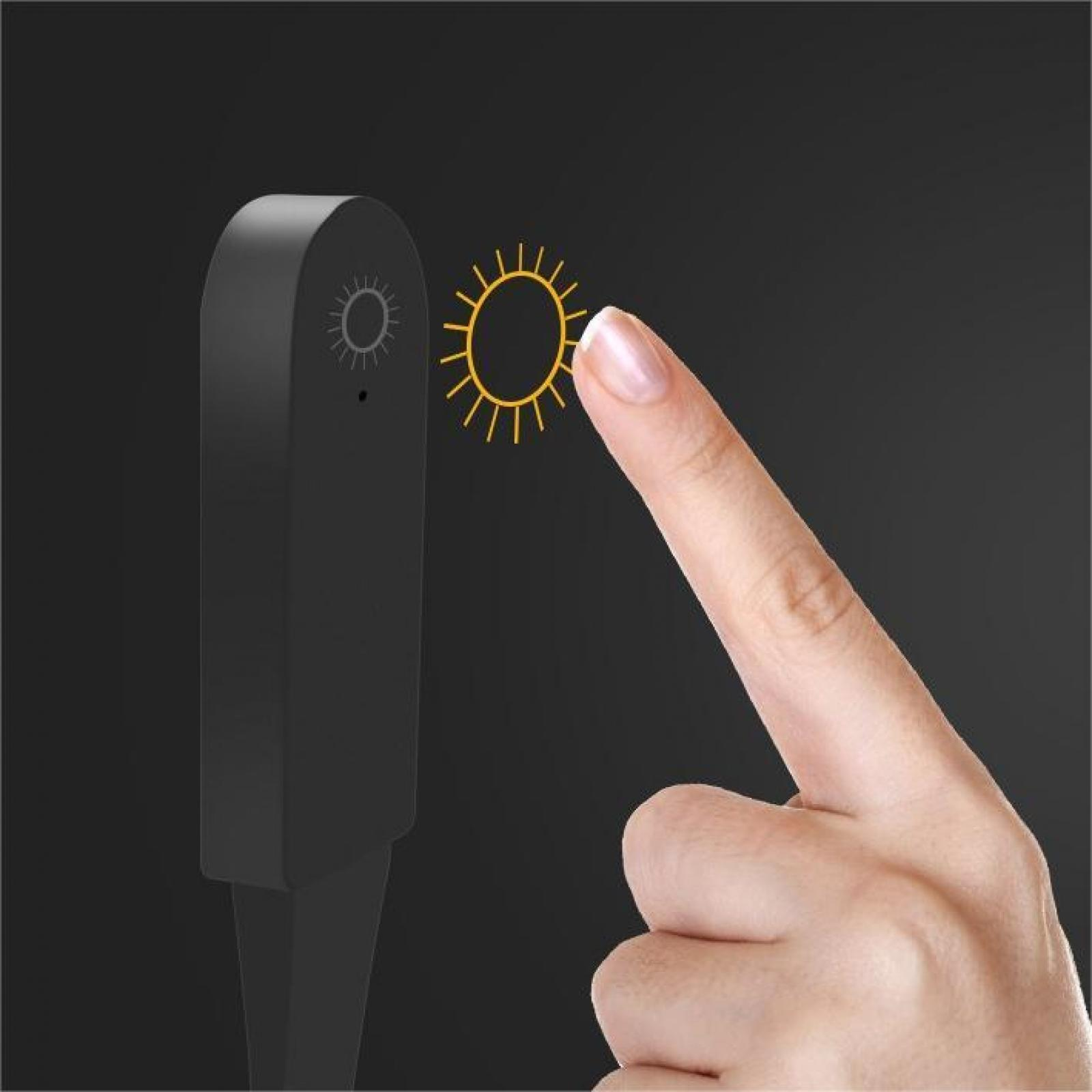 Ein Finger berührt ein Sonnensymbol neben einem schwarzen Gerät. Der Hintergrund ist ebenfalls schwarz.