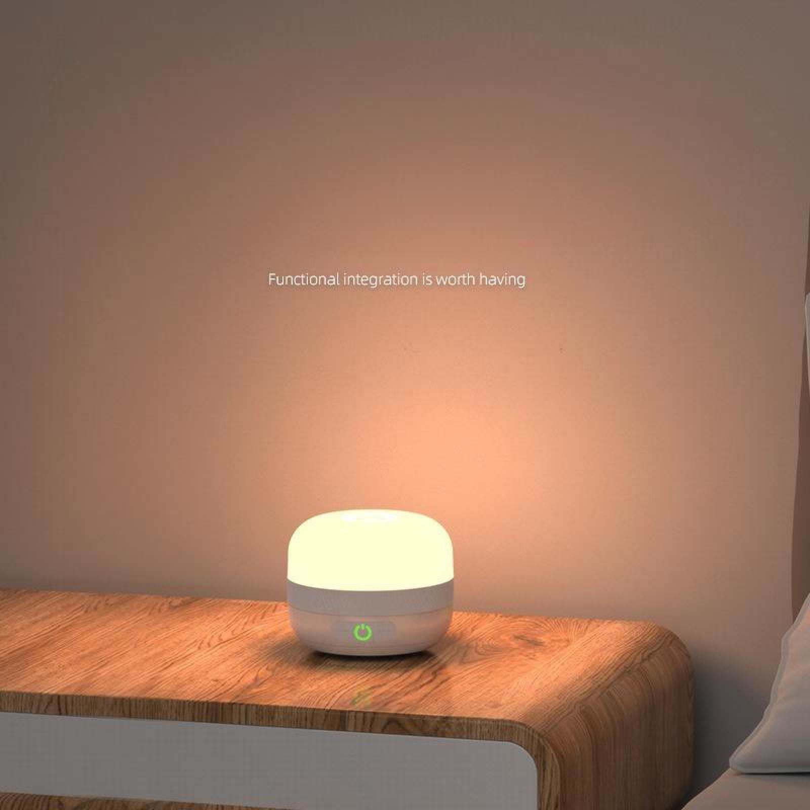 Eine leuchtende weiße Lampe steht auf einem hölzernen Nachttisch. Eine Wand mit Text: 'Funktionale Integration lohnt sich' ist dahinter.