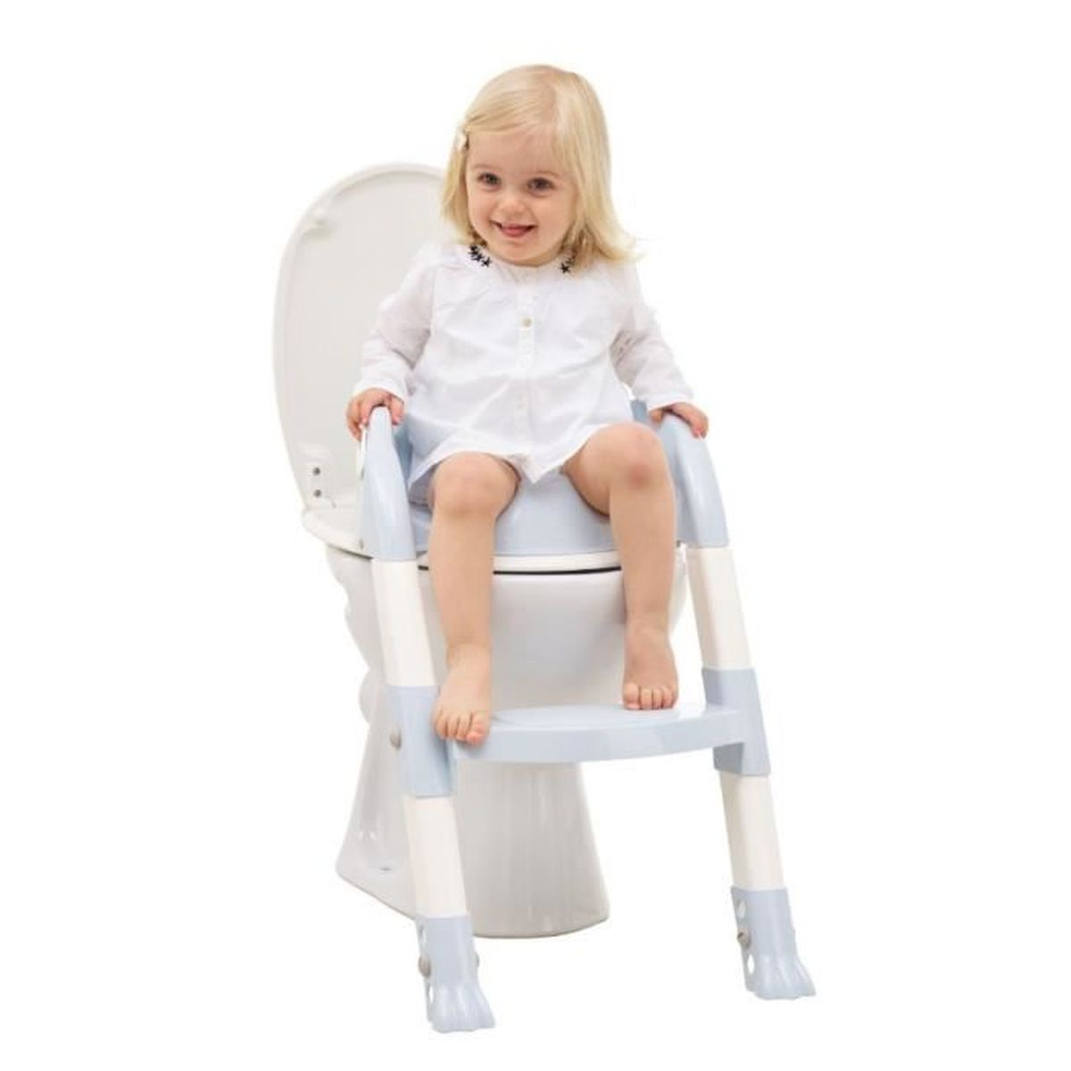 Ein lächelndes Kleinkind sitzt mit einem Tritthocker auf einer Toilette. Sie trägt ein weißes Kleid. Der Hintergrund ist weiß.
