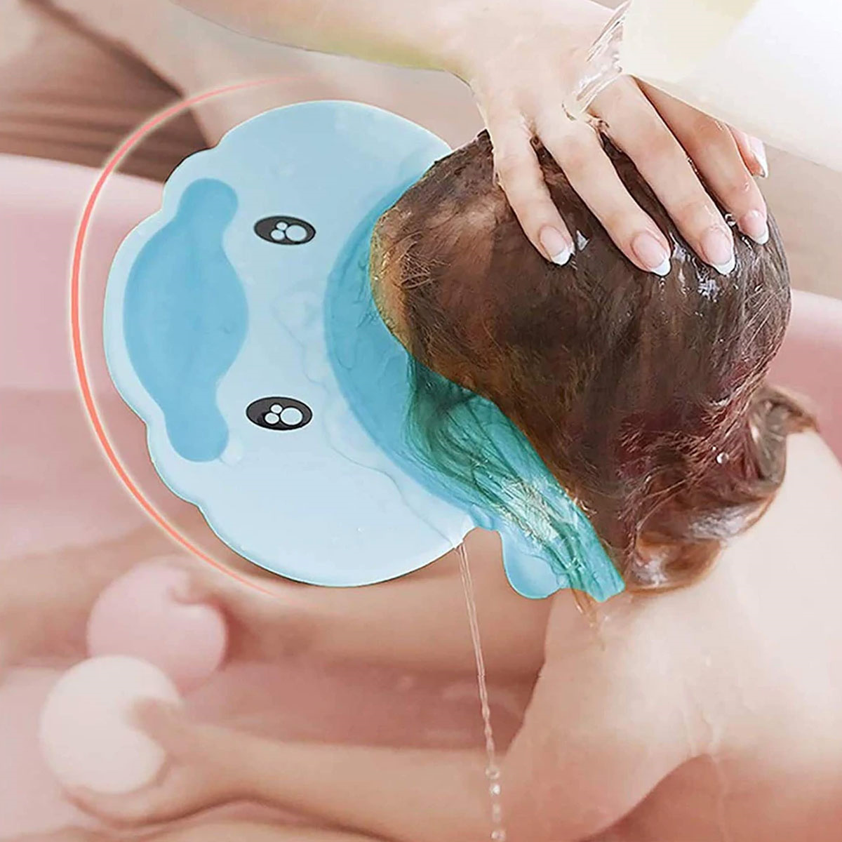 Eine Person wäscht Haare über einem blauen Becken. Wasser fließt aus dem Haar. Die Szene spielt in einer rosa Badewanne. Eine Hand ist sichtbar.