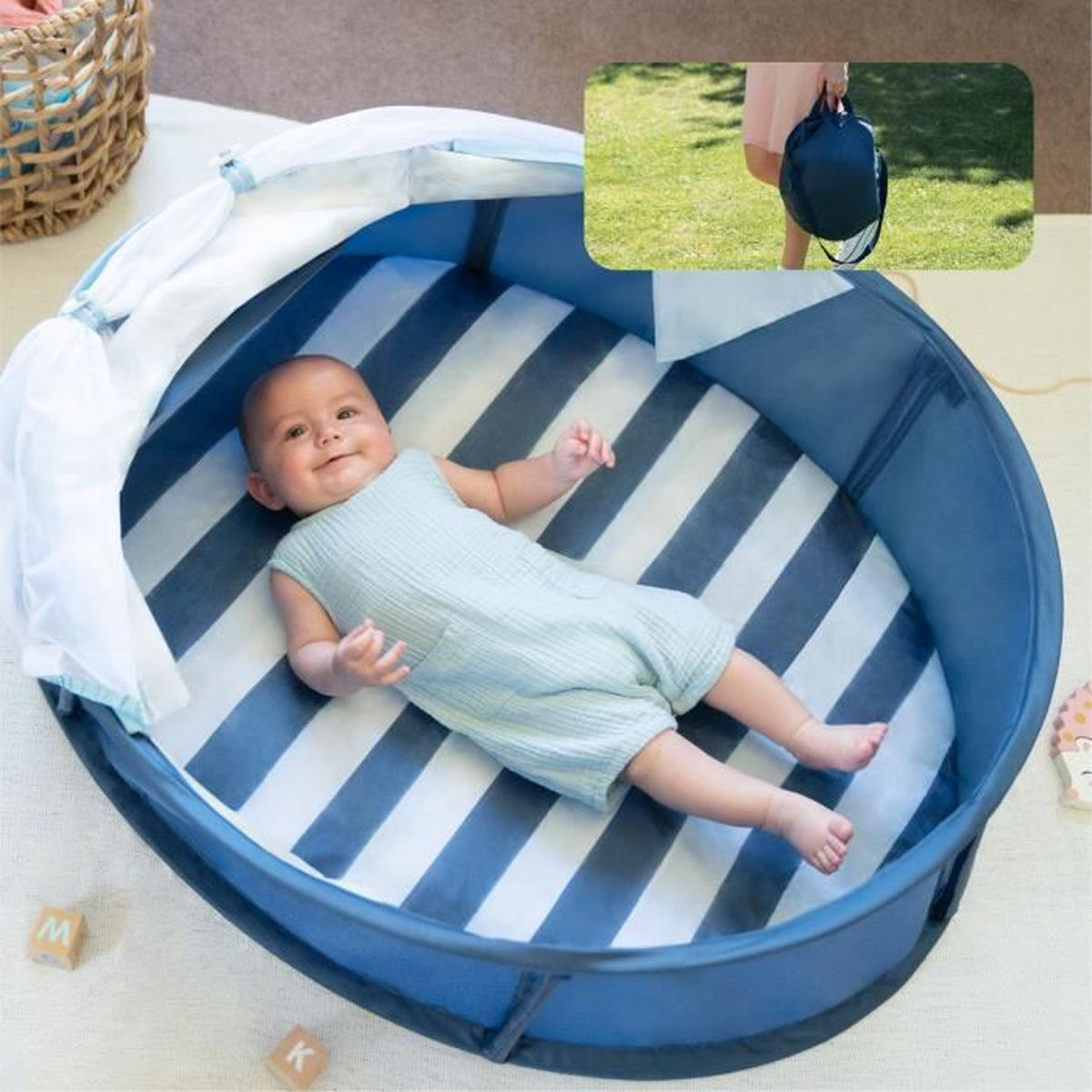 Ein Baby liegt in einem blau-weiß gestreiften Laufstall. Eine Person hält eine dunkle Tasche. Ein Weidenkorb steht daneben.