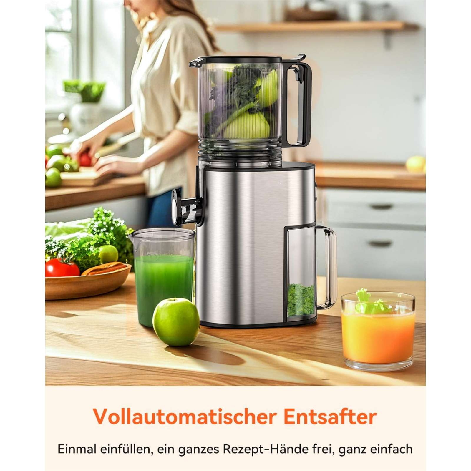 Ein Entsafter mit Obst und Gemüse. Eine Person ist im Hintergrund. Grüner Saft und Orangensaft in Gläsern.