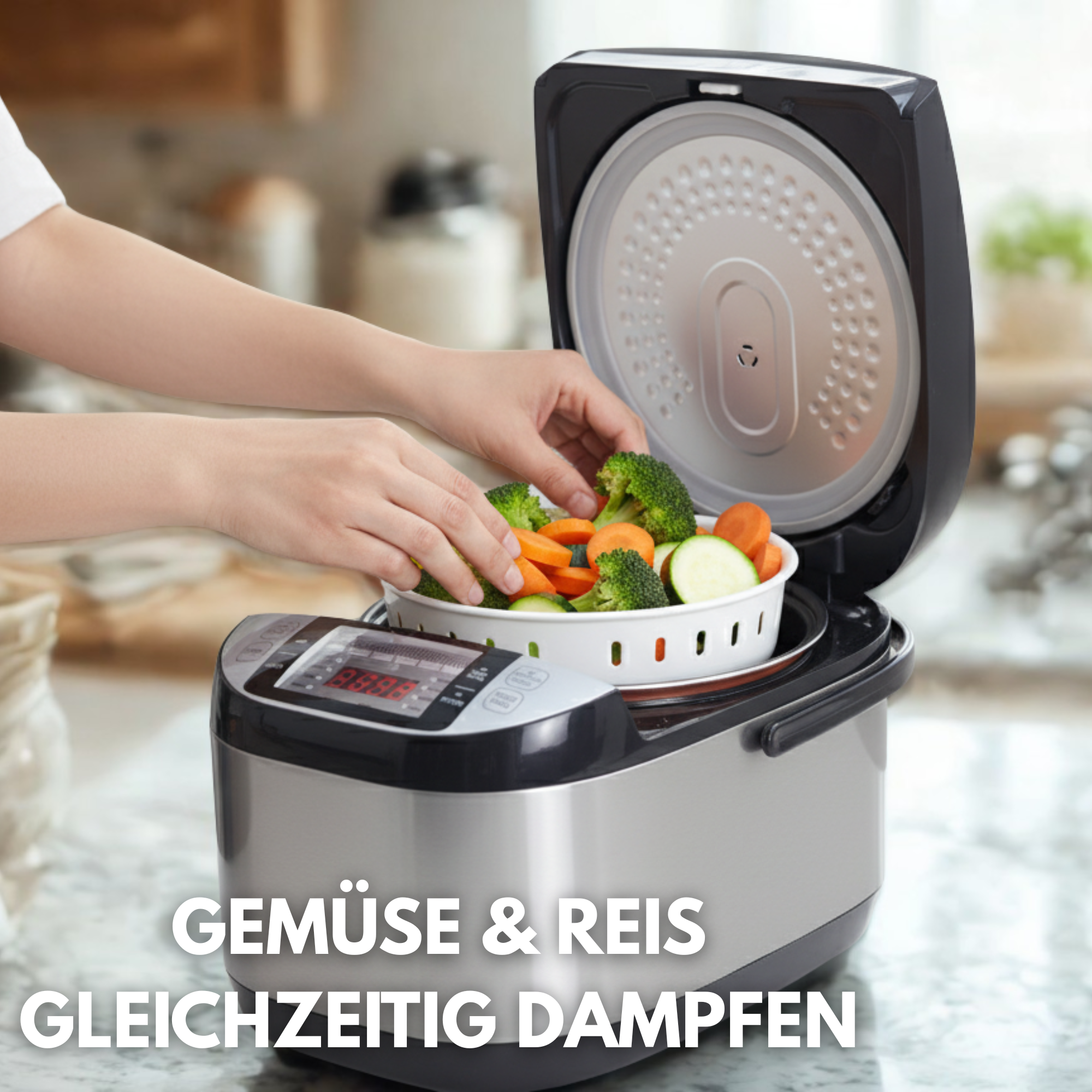Eine Person legt Gemüse in einen Dampfgarer. Brokkoli, Karotten und Zucchini sind sichtbar. Das Gerät ist silber und schwarz.